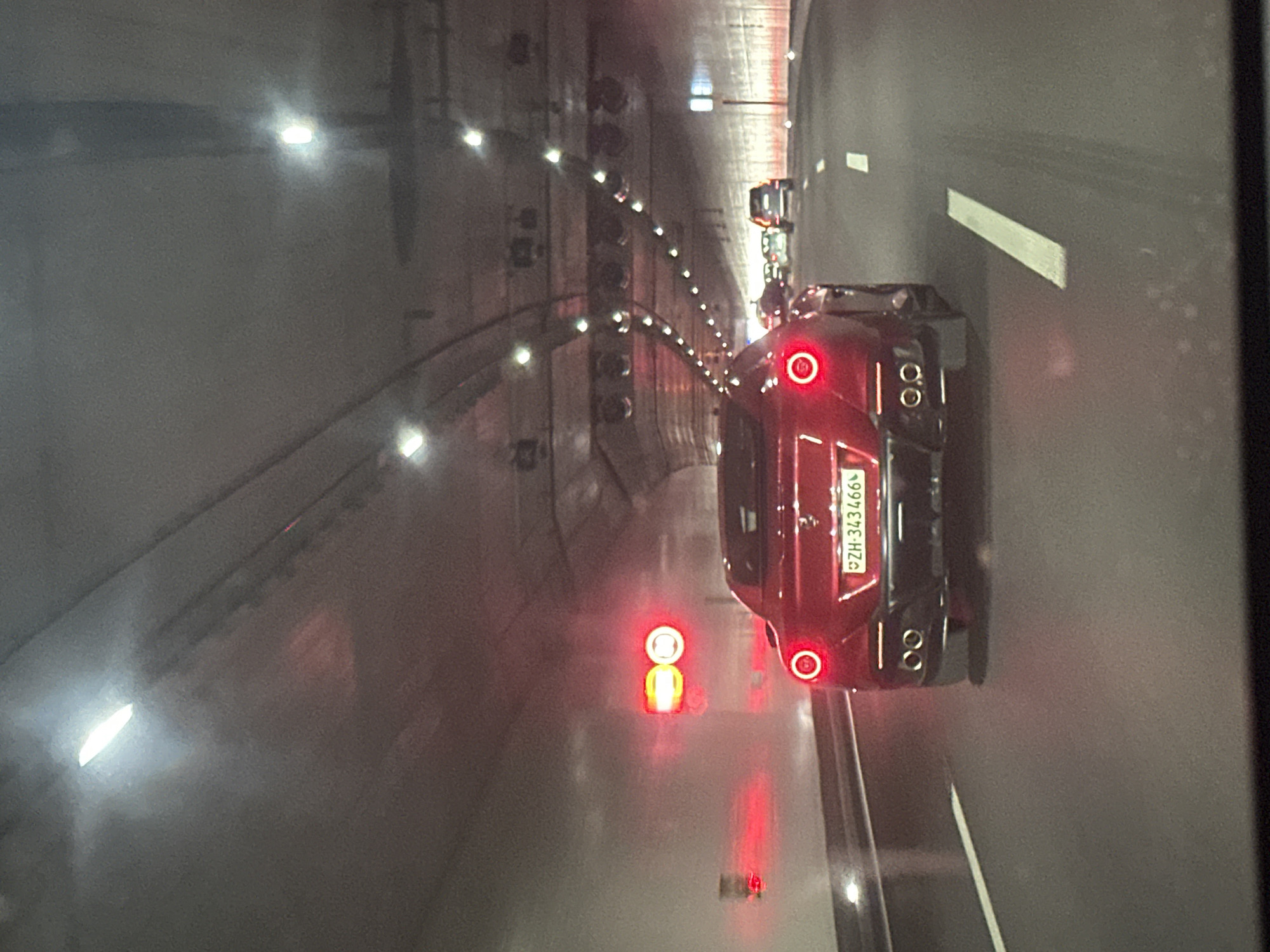 Red sports car travels through Zurich tunnel during afternoon traffic