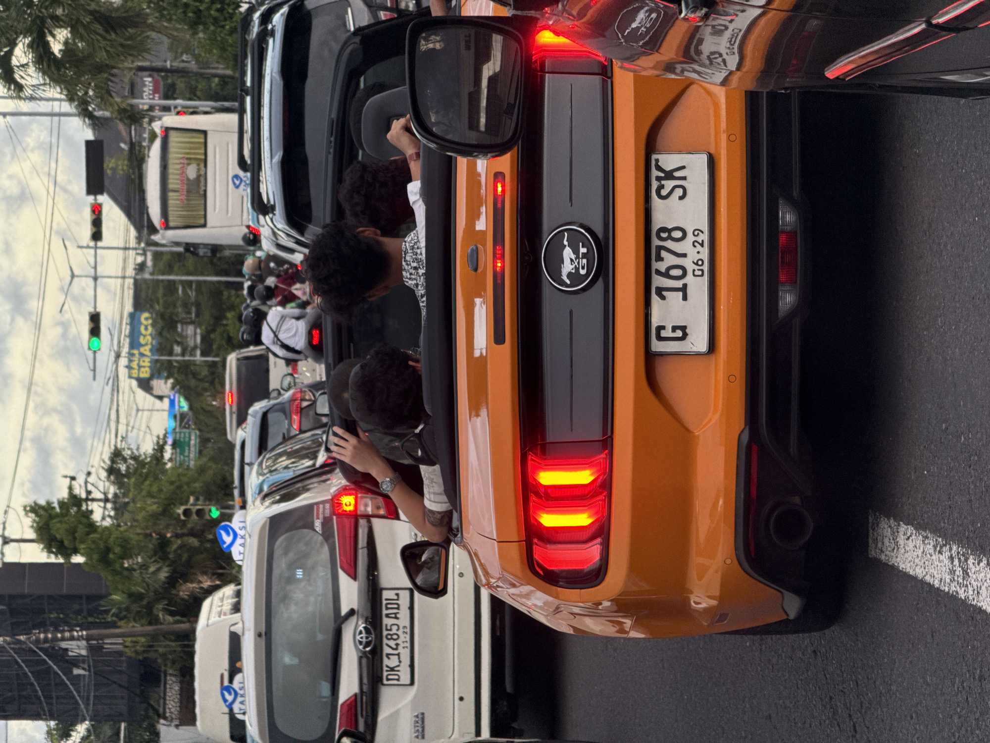 Traffic jam blocks vehicles including orange Mustang in Kuta