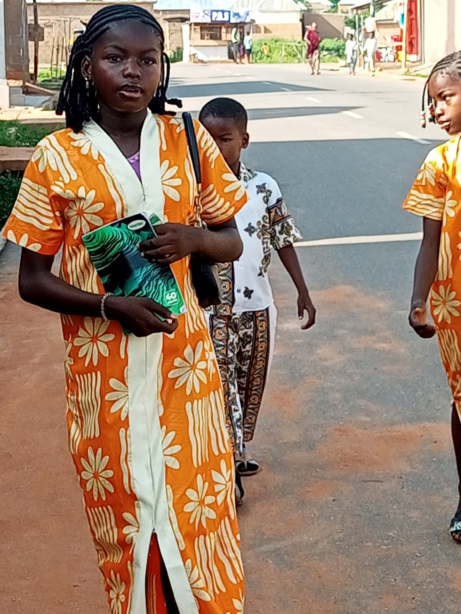 Street scene in Tumfure, Nigeria — pedestrians on a paved road