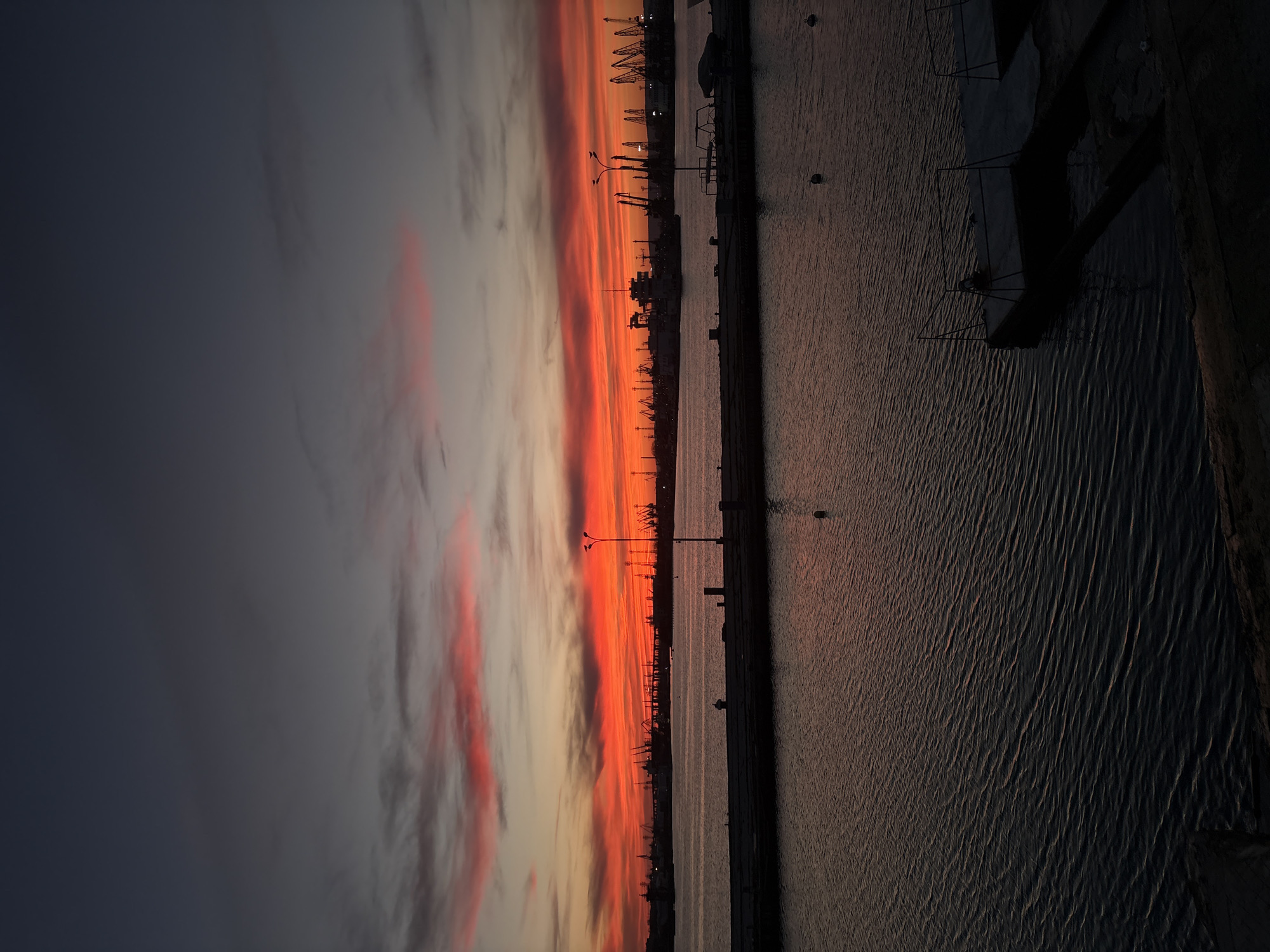 Sunset observed over Varna port with silhouetted cranes