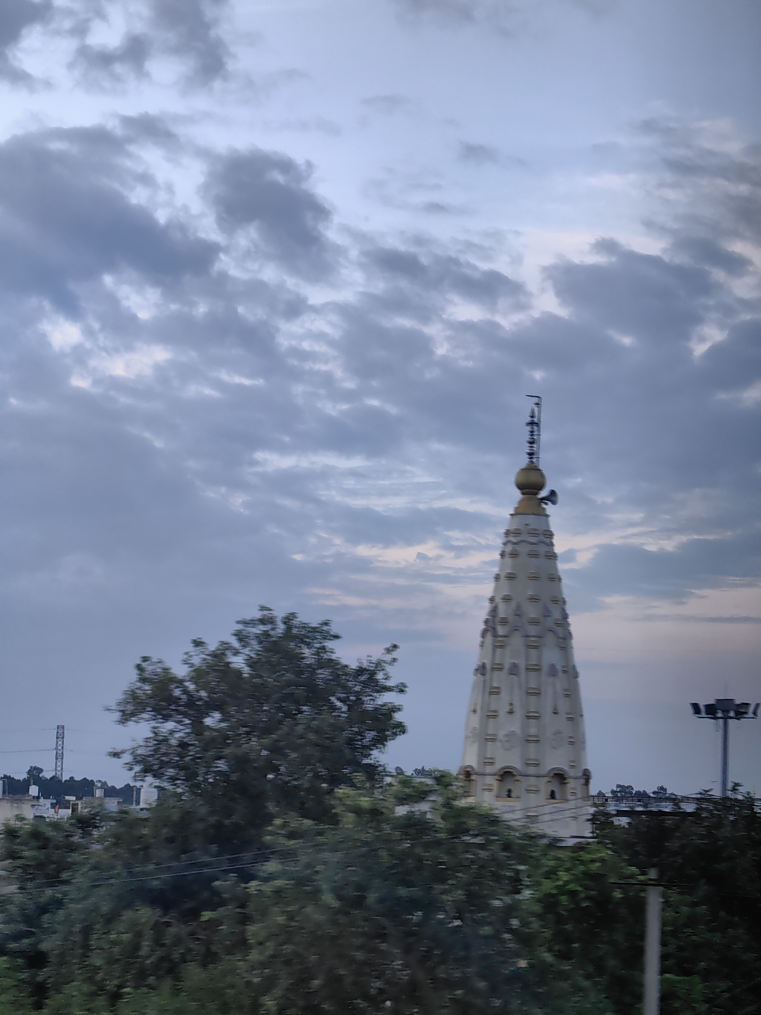 Tiered white temple spire reaching skyward in Uchana, India