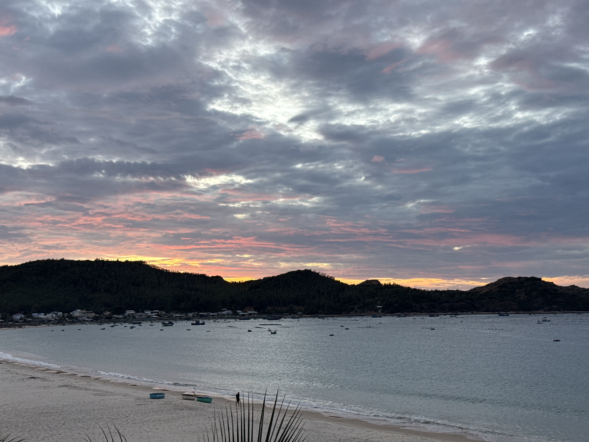 Sunset beach scene with dramatic cloudy skies and calm water