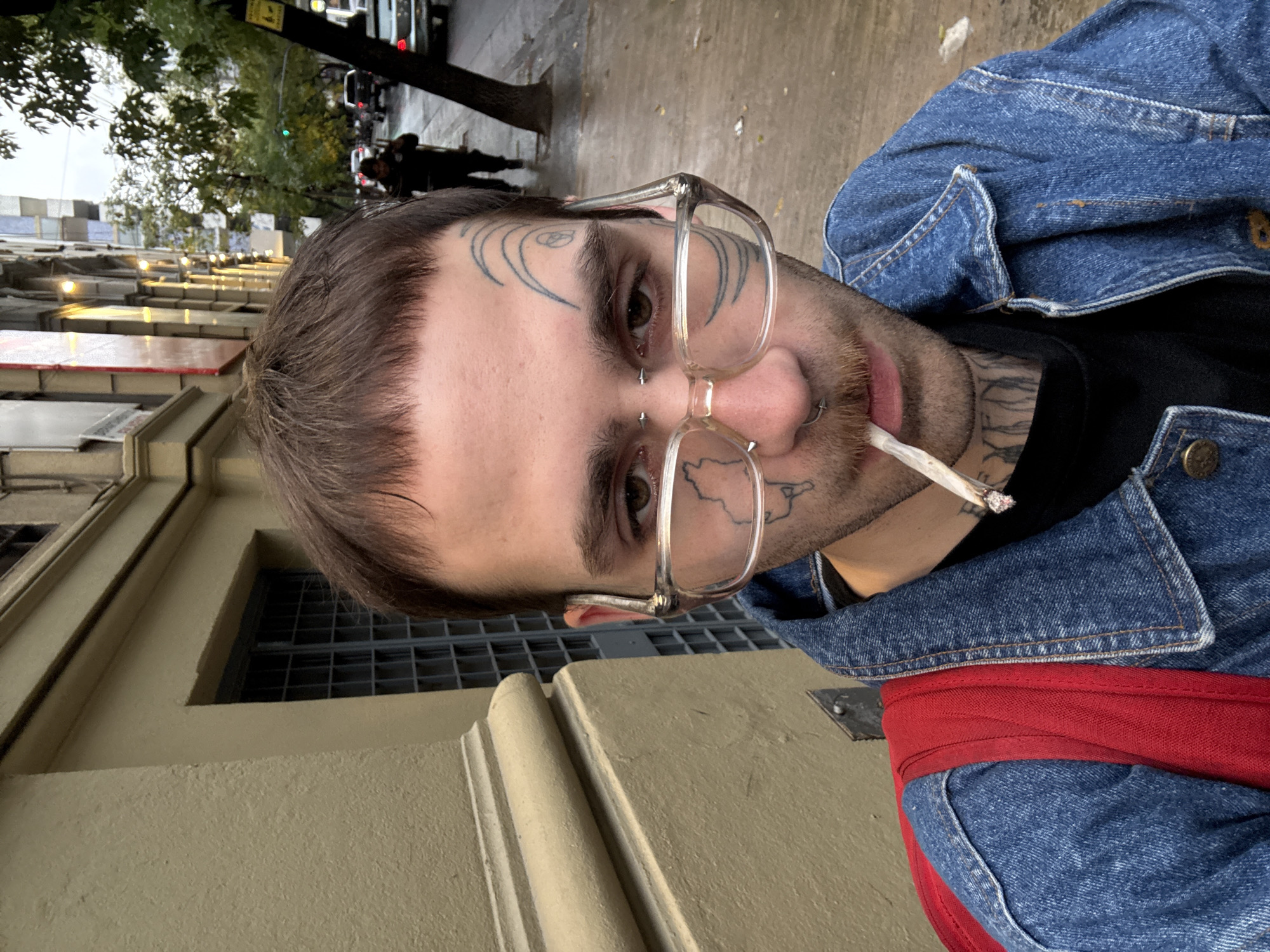 Man with facial tattoos smokes cigar on Buenos Aires sidewalk