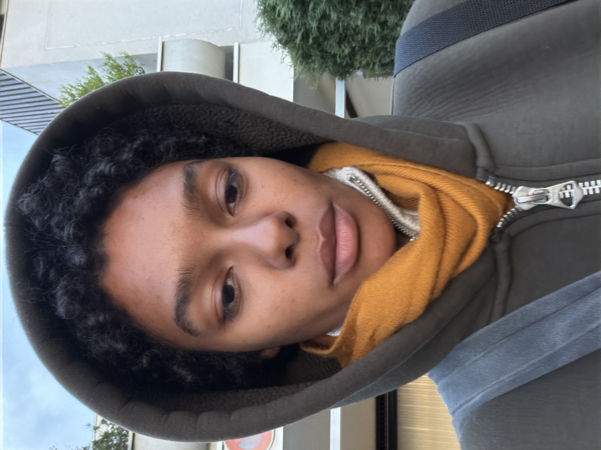 Person in gray hoodie and yellow scarf photographed in France
