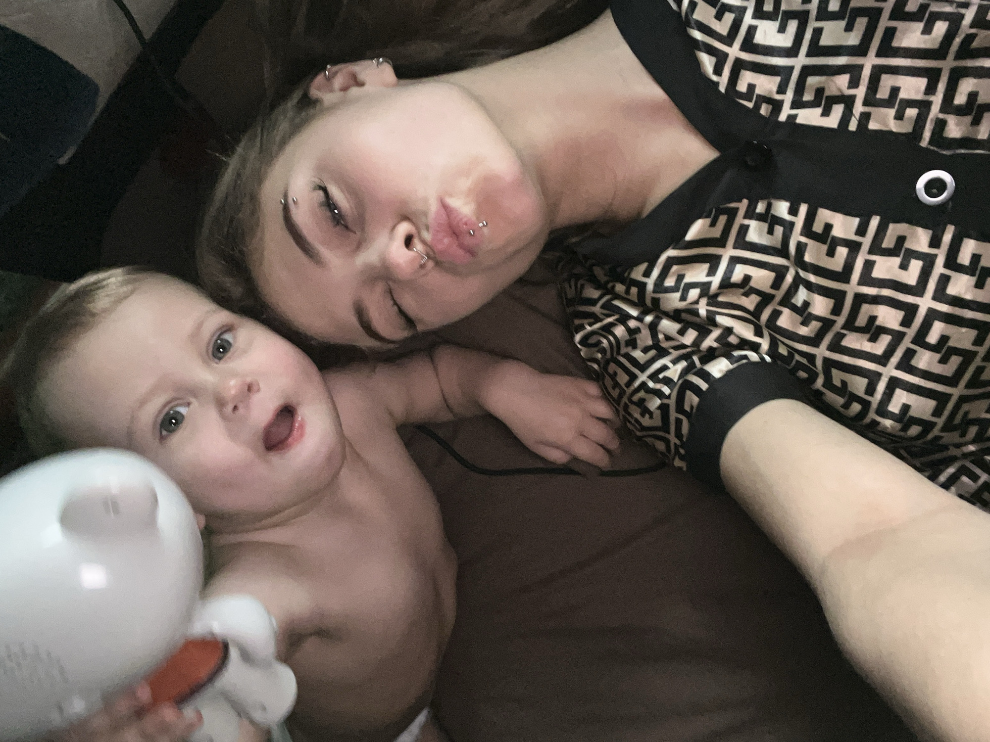Woman with piercings rests beside baby in Foki, Russia