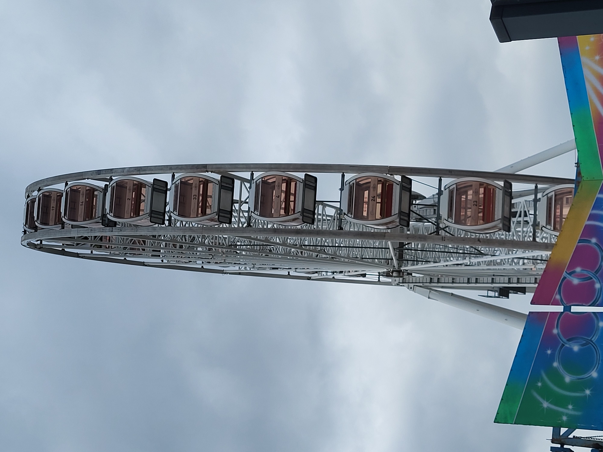 Large white Ferris wheel operates under partly cloudy skies