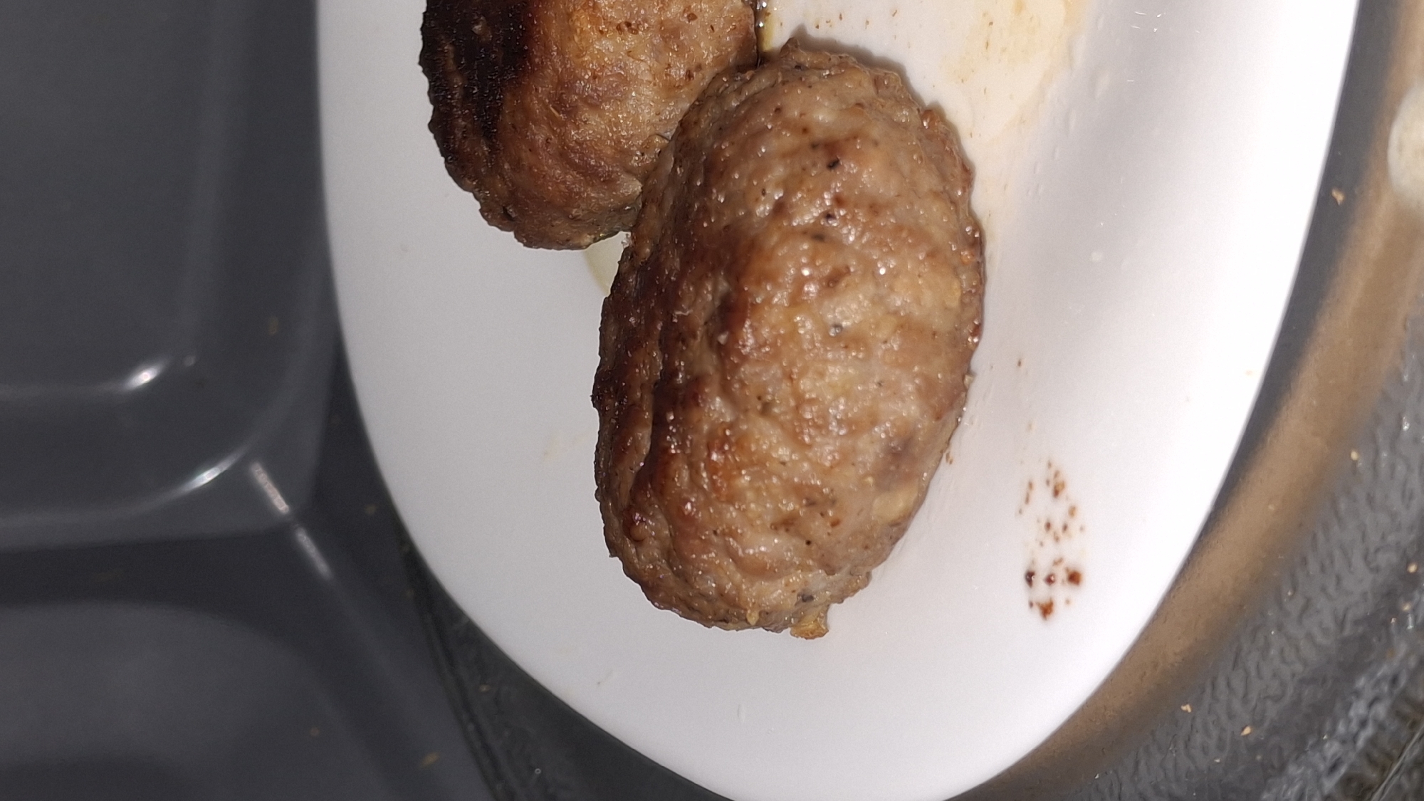 Two meatballs documented on white plate at unknown location