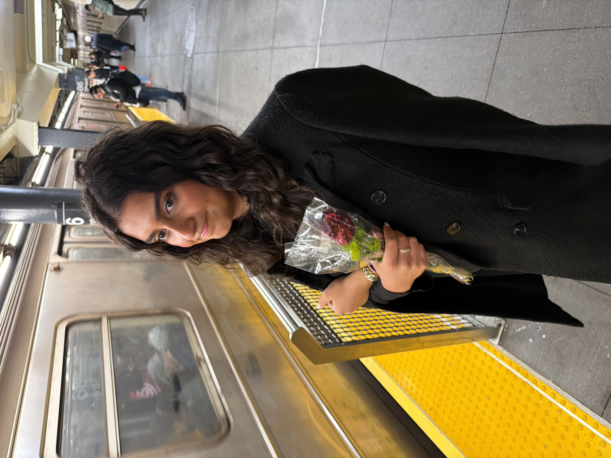 Woman holds flower bouquet on NYC subway platform early morning