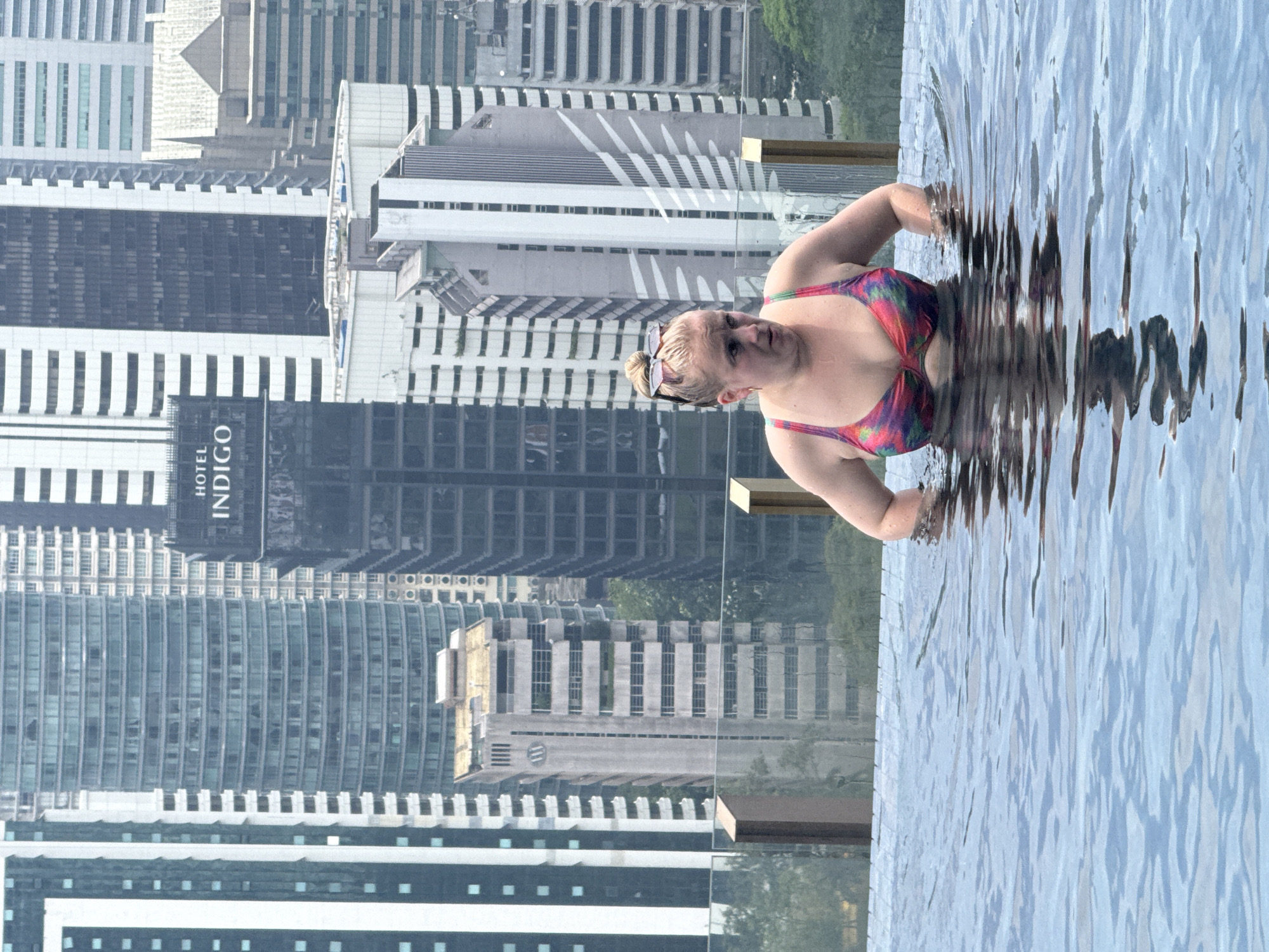 Woman enjoys early morning pool time above Kuala Lumpur skyline