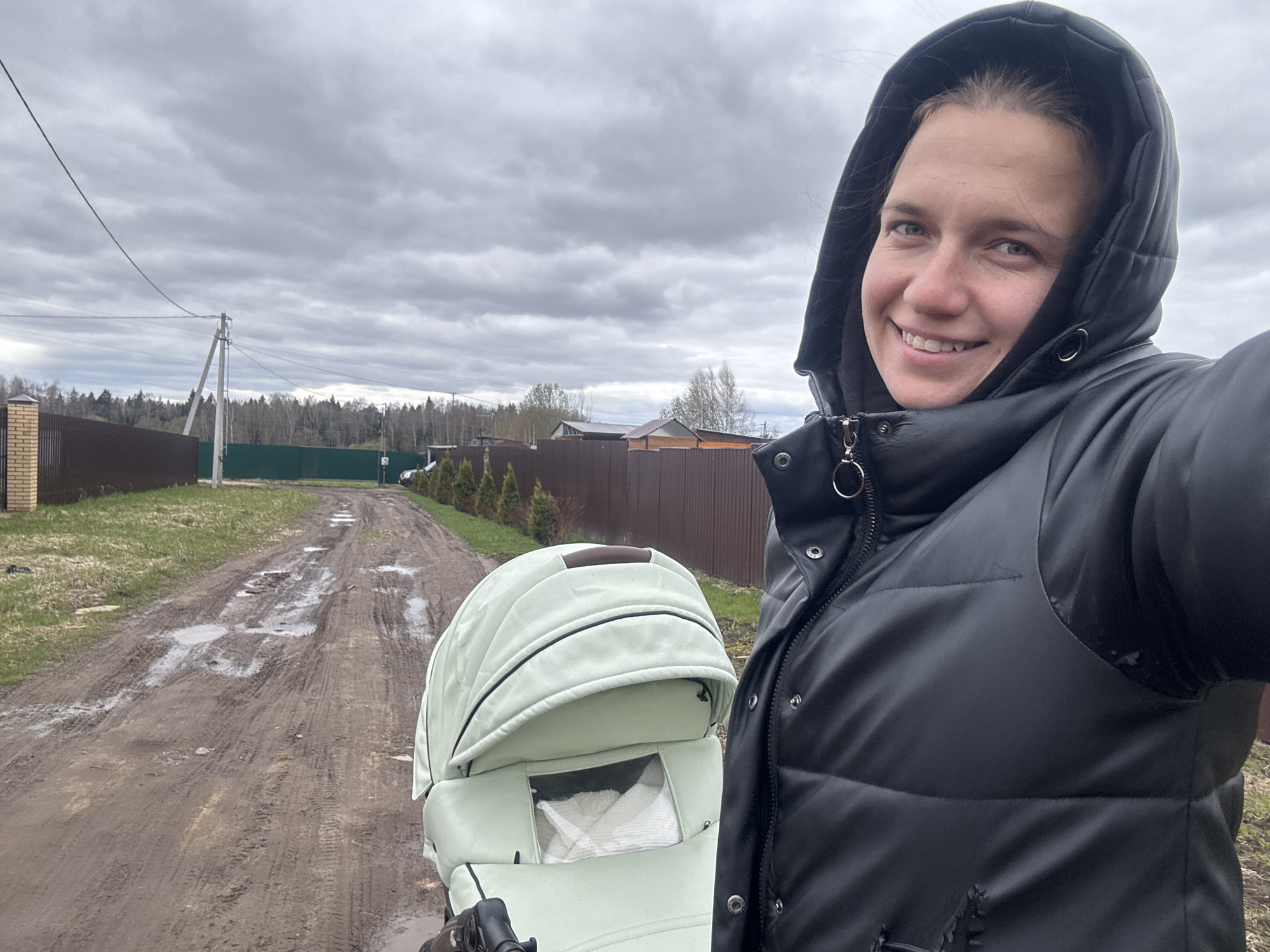 Woman with stroller walks muddy roads in Russian village
