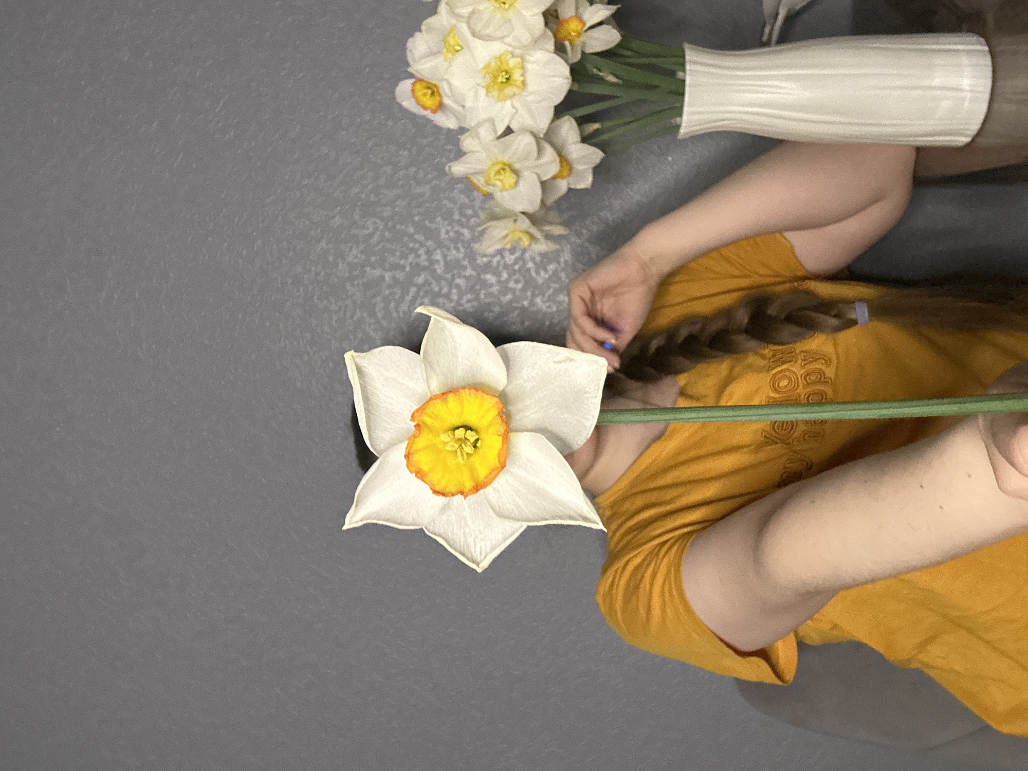 Woman in yellow shirt documents spring flowers at home