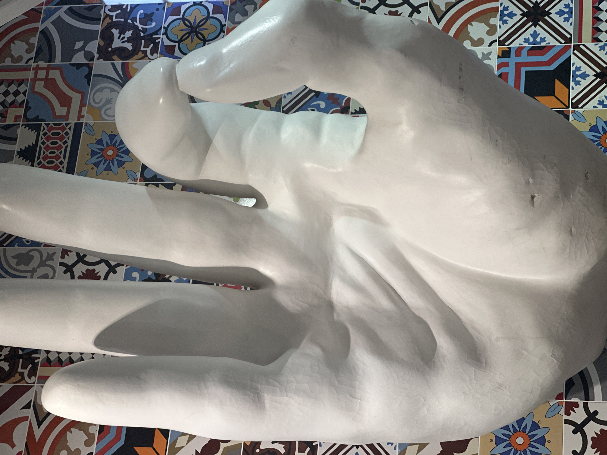 White hand sculpture observed against colorful tiles in Kazan