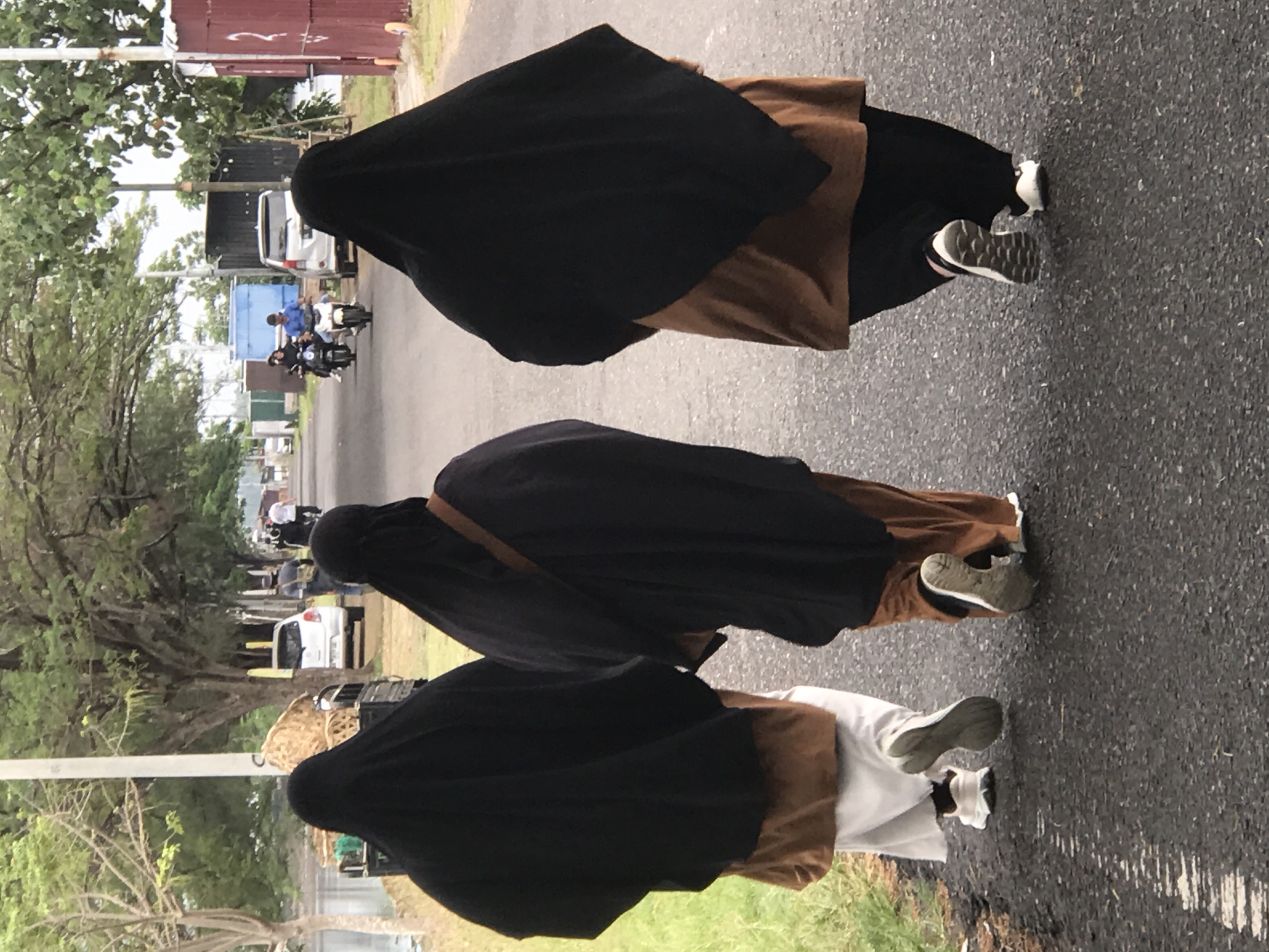 Three niqab-wearing individuals walk street in Lhokseumawe, Indonesia