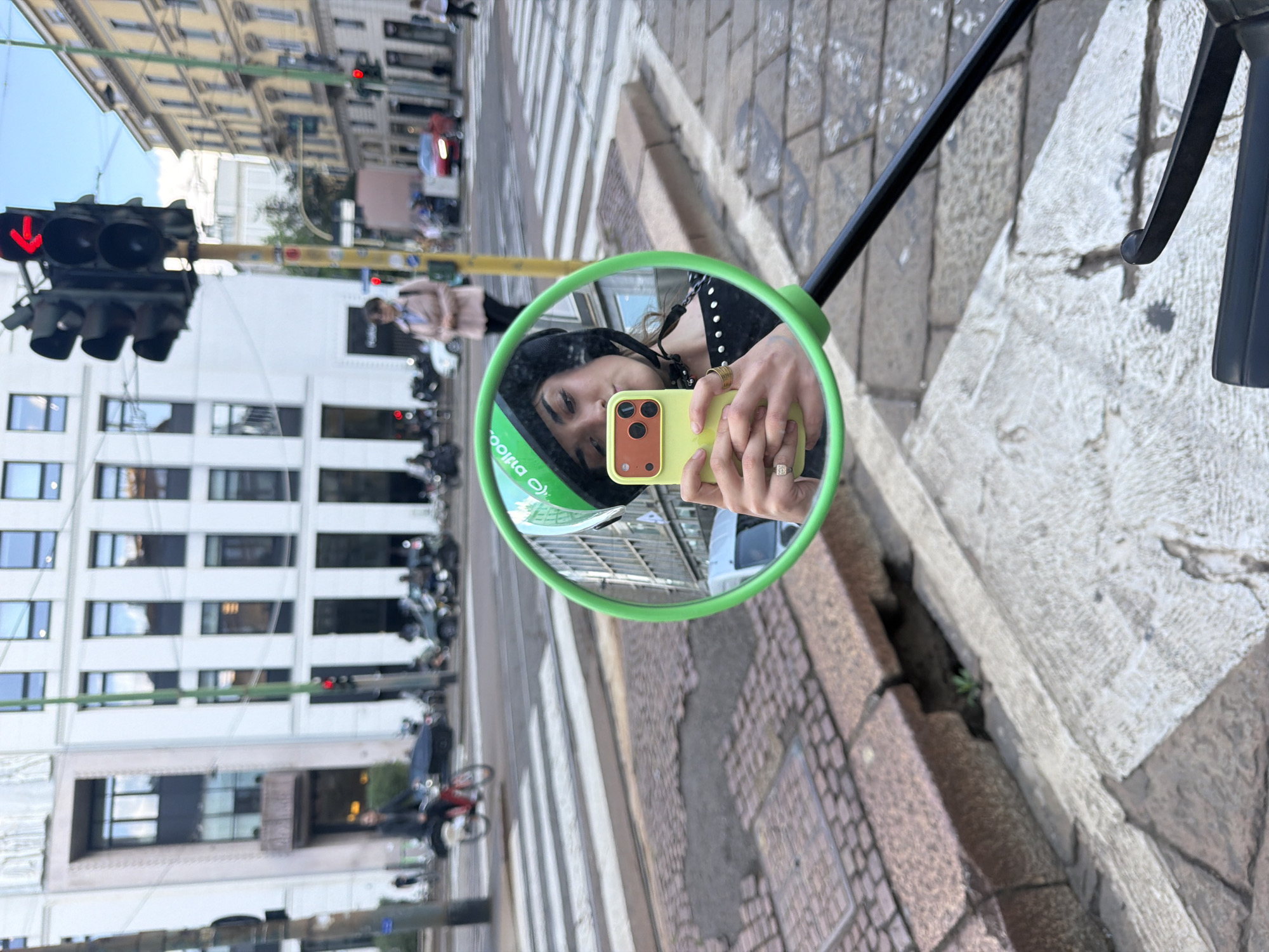Milan street scene captured in green bike mirror reflection