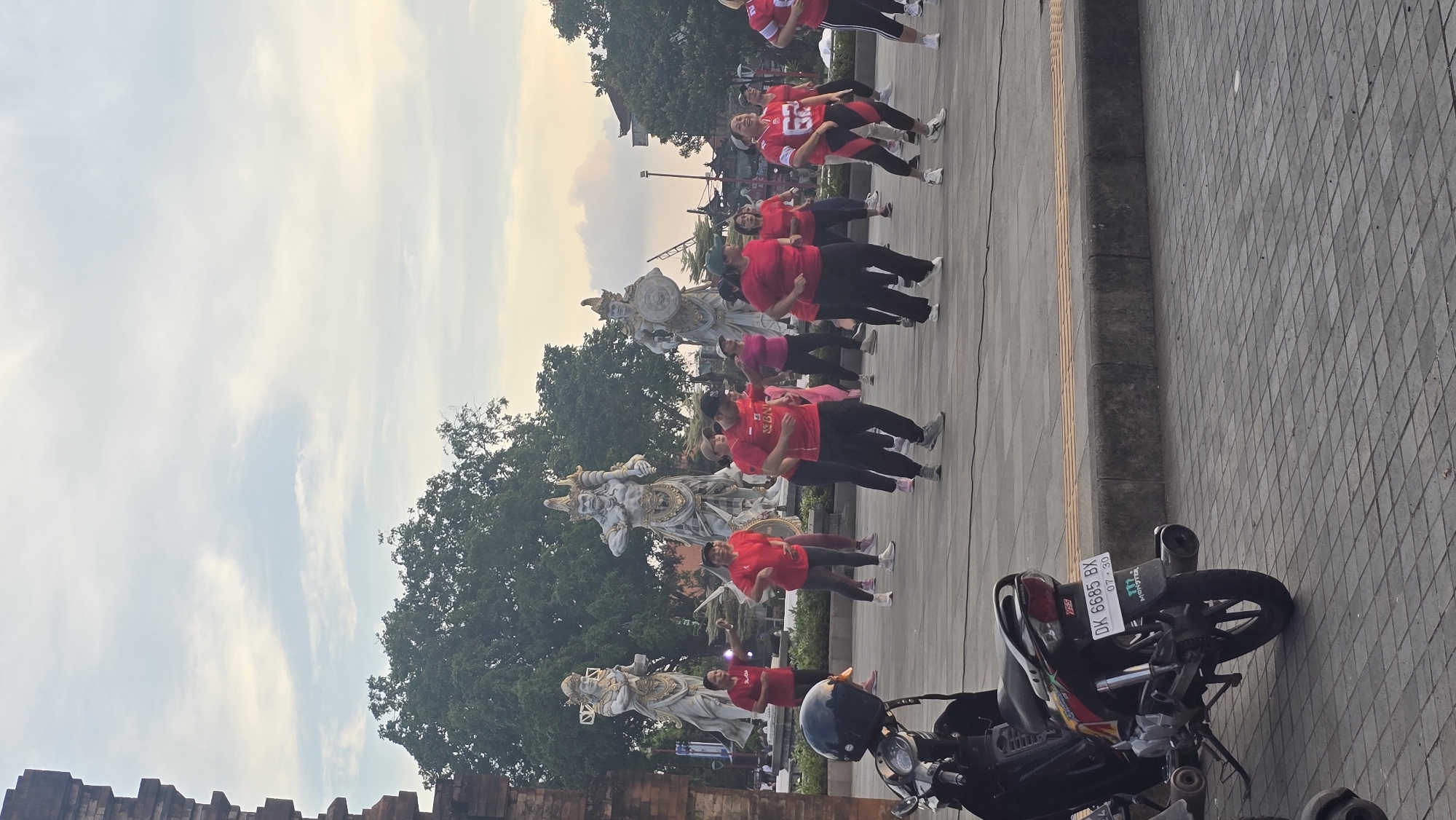 Women's exercise group gathers near traditional statues in Gianyar