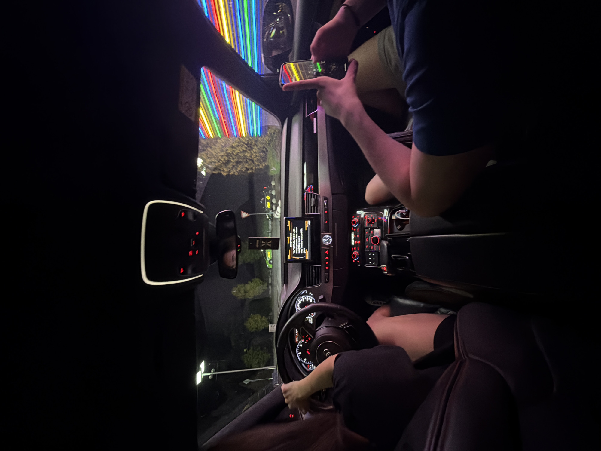 Cruising Ruse at night past neon-lit city landmarks
