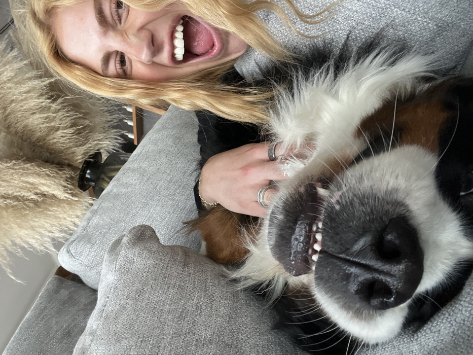 Woman relaxes with Bernese Mountain Dog on couch