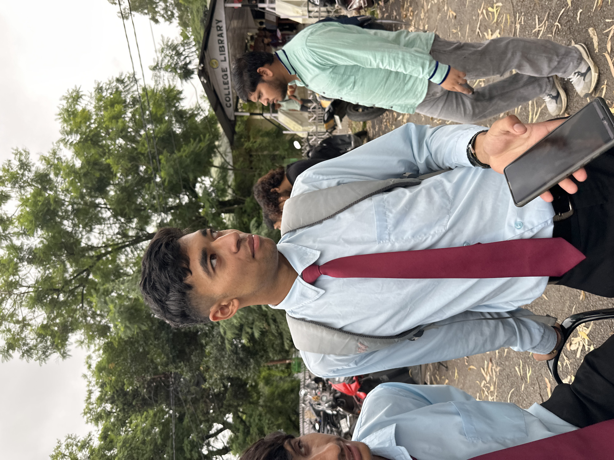 Students outside a college library on a rainy hillside campus