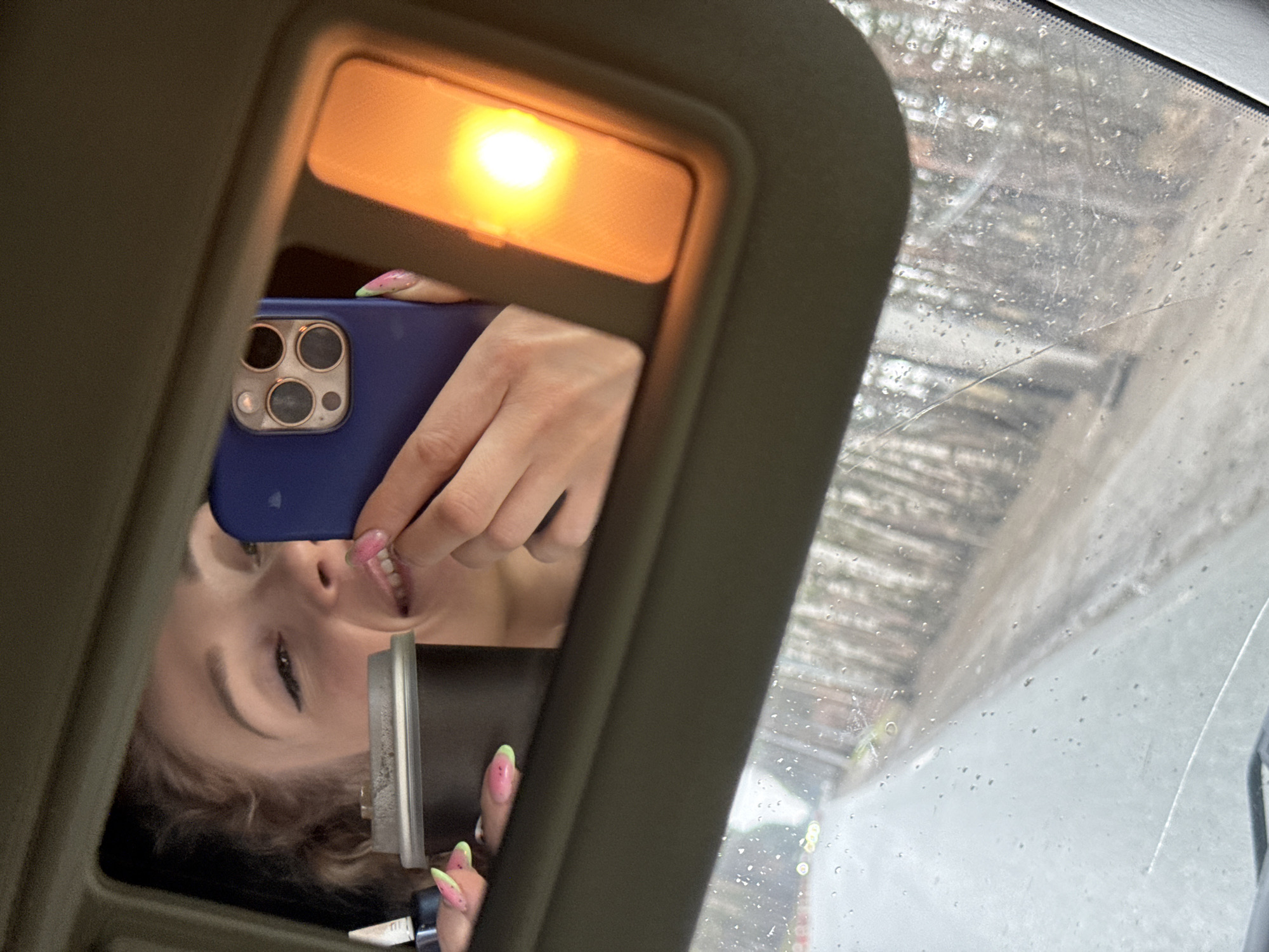 Woman takes selfie in car mirror during rain