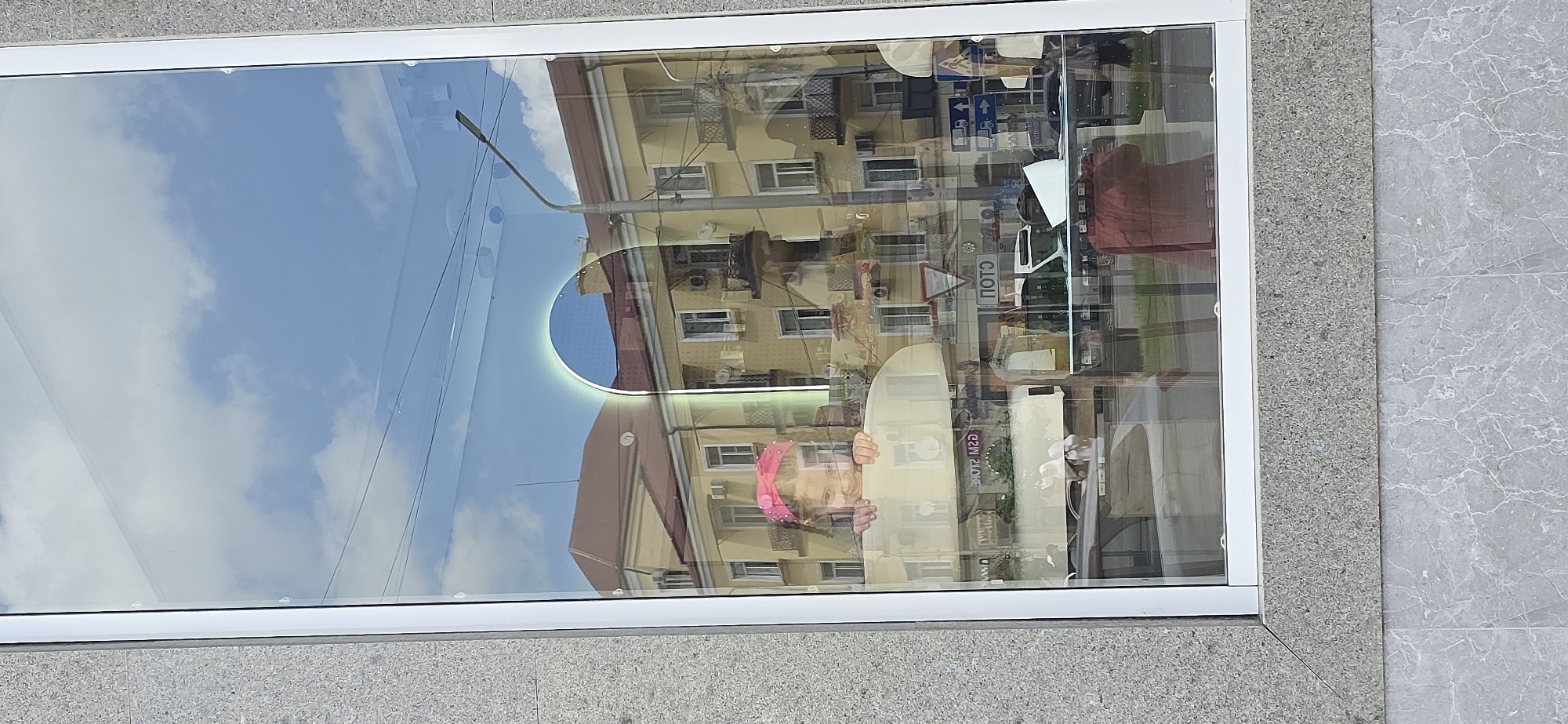 Street reflection captured in Grozny storefront window