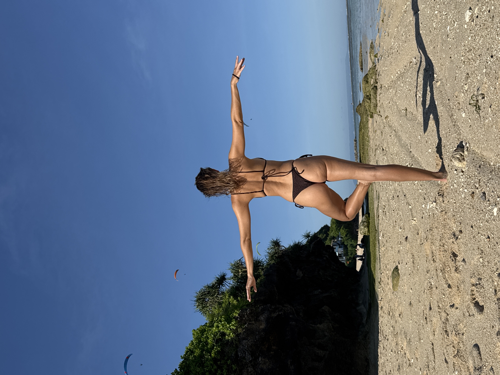 Woman practices beach yoga poses in Kuta Selatan Indonesia