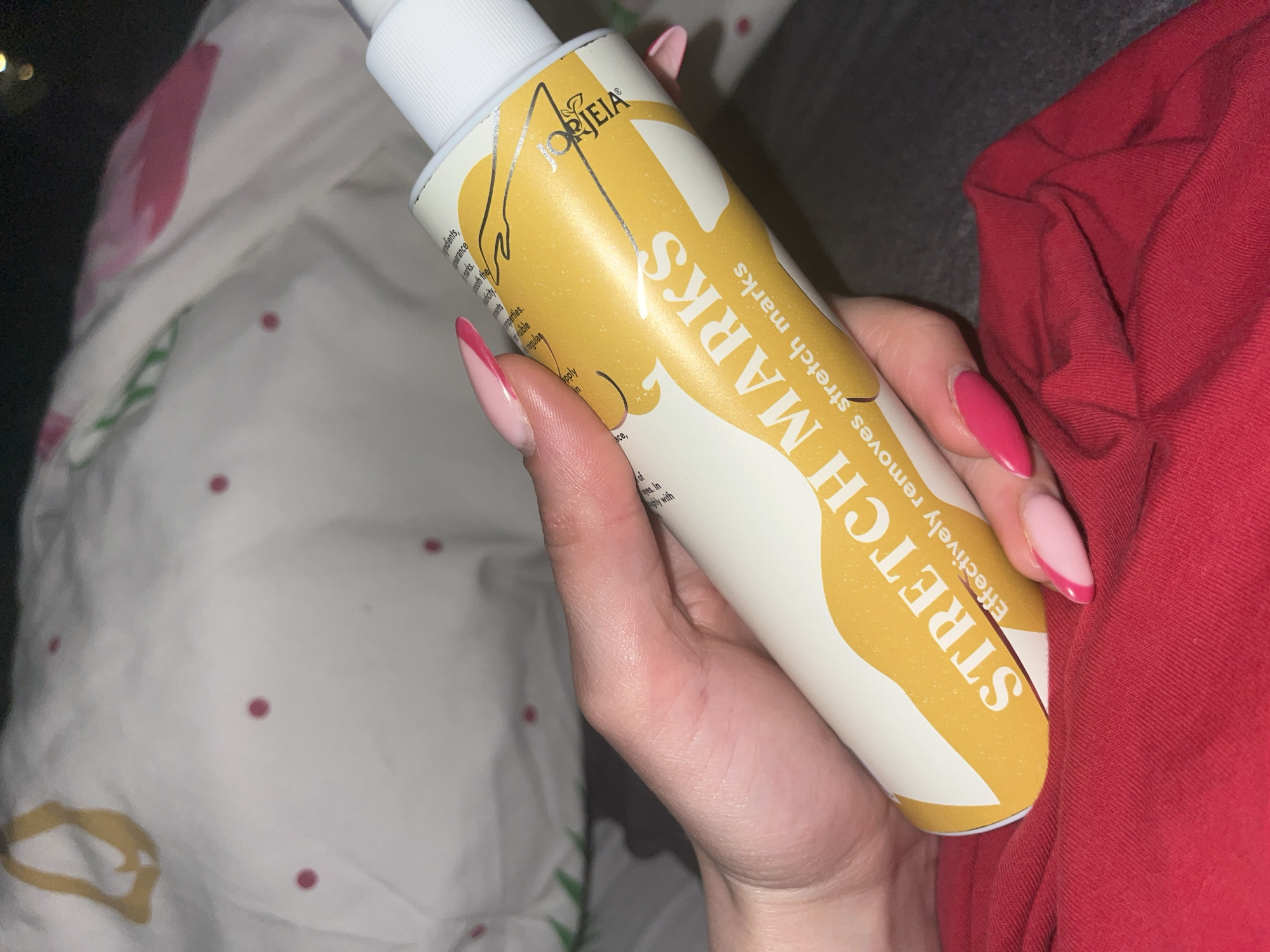 Woman displays stretch mark cream in bedroom in Pernik