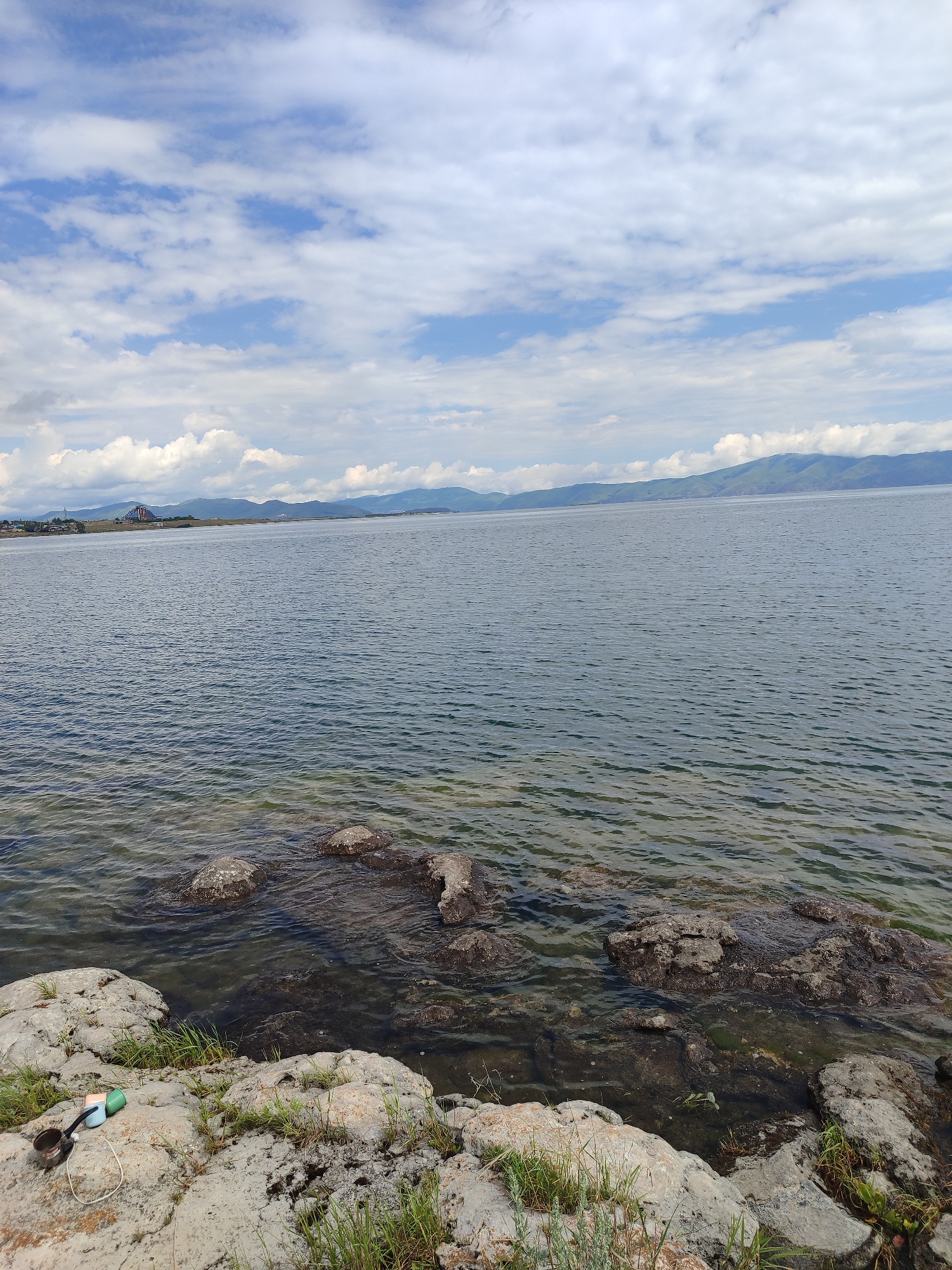 Rocky Lake Sevan shoreline with distant blue structure, Armenia