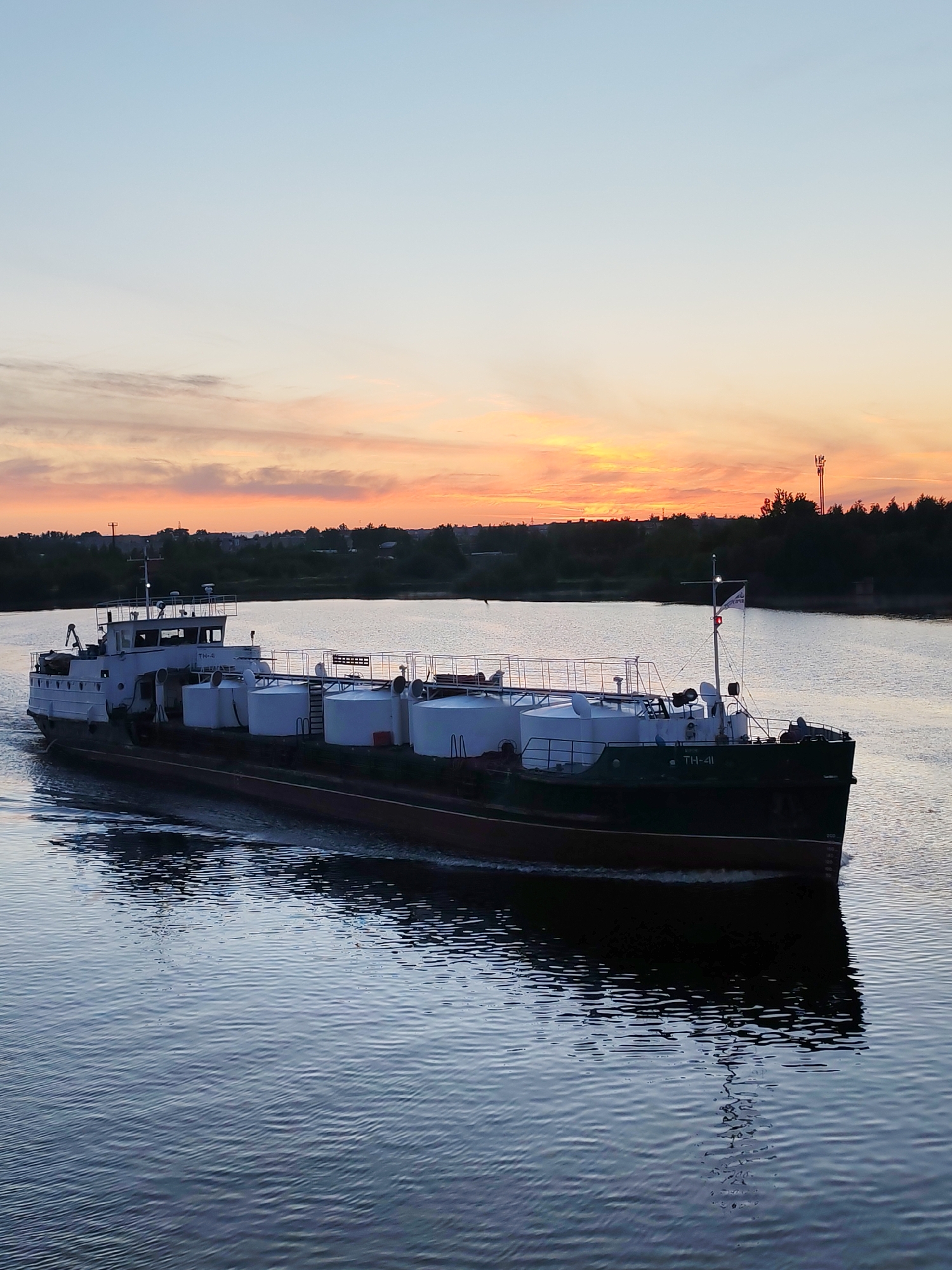 Commercial barges navigate river during dawn hours, witness documents traffic