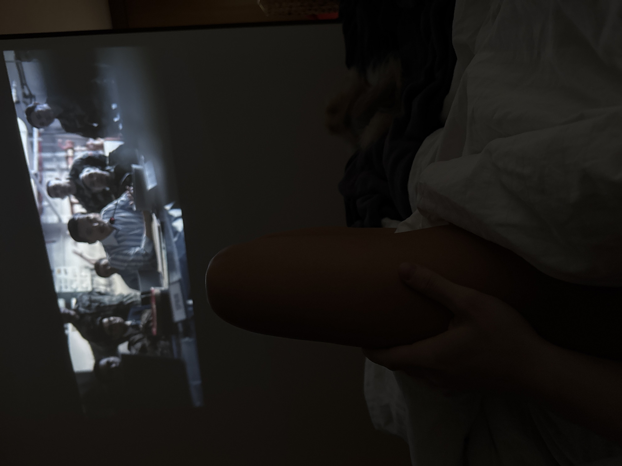 Person rests with injured leg while watching projected film