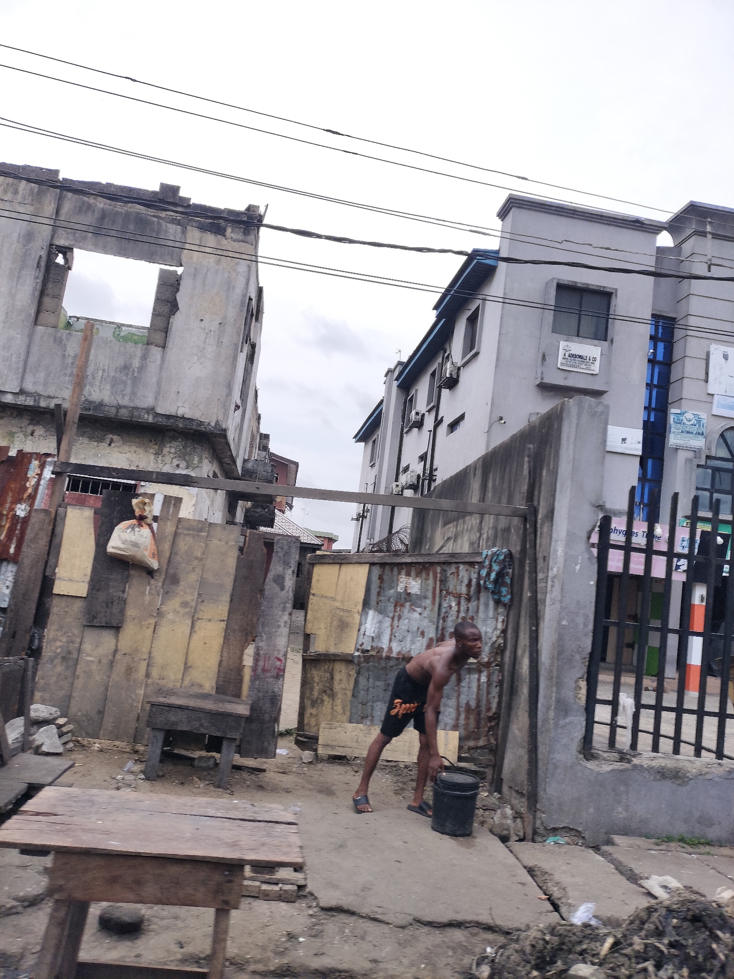 Man carries bucket near concrete structure in Alaiyabiagba, Nigeria