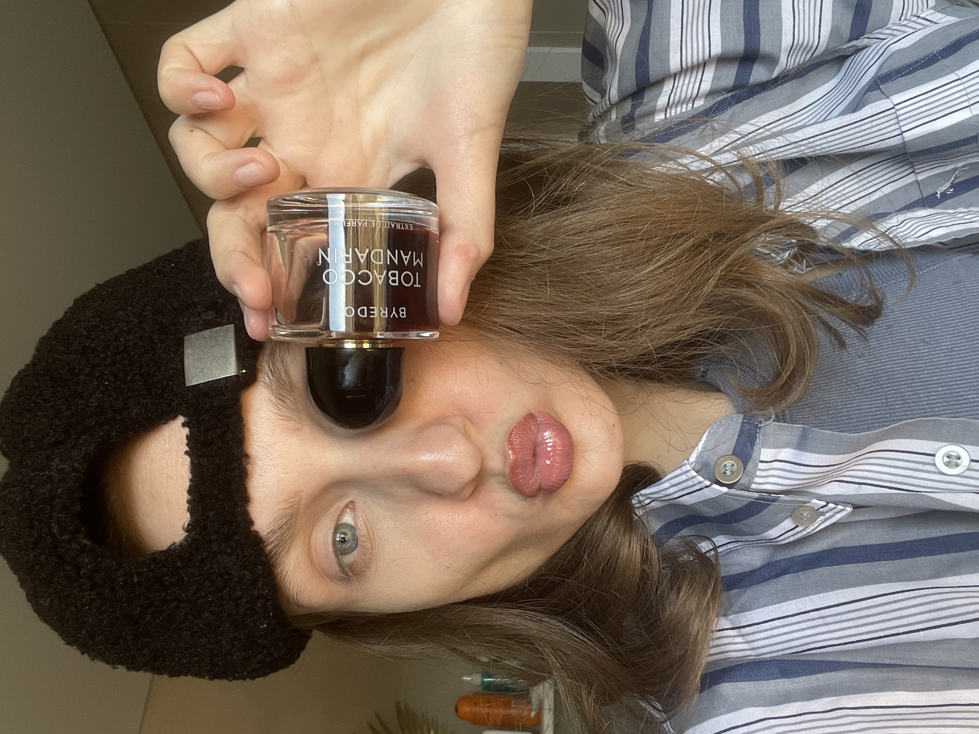 Person poses with luxury perfume bottle in rural Russia