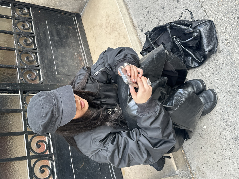 Person in military cap sits by ornate gate in Paris