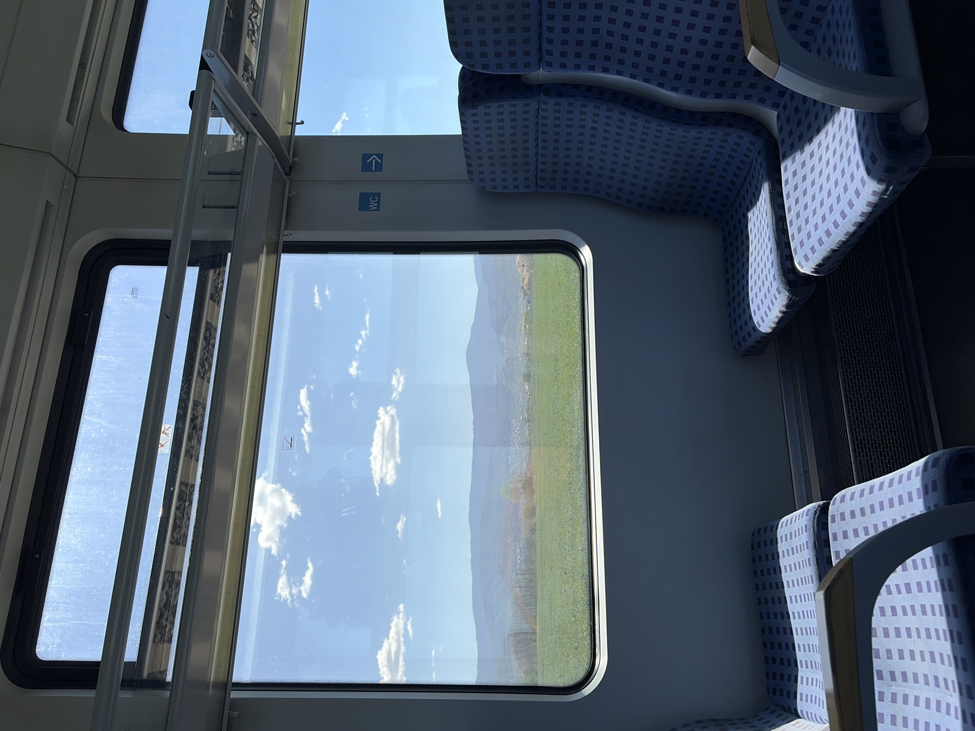 Train passengers observe countryside views, station platform activity documented