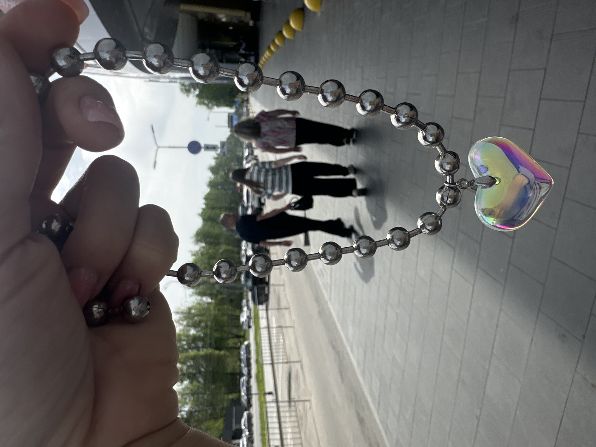 Person documents iridescent heart necklace in Nizhny Novgorod street scenes