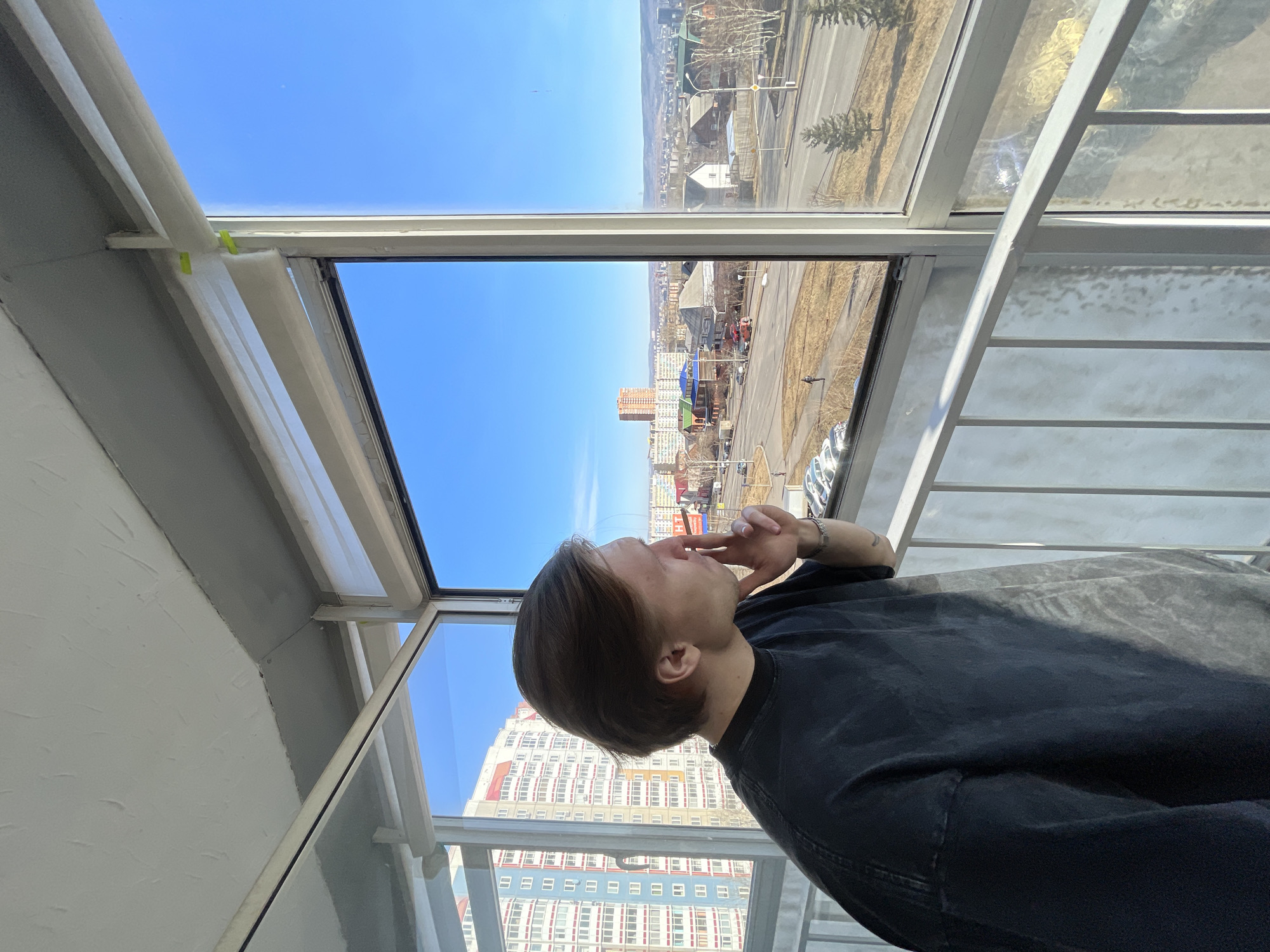 Person gazes at cityscape from window in Krasnoyarsk