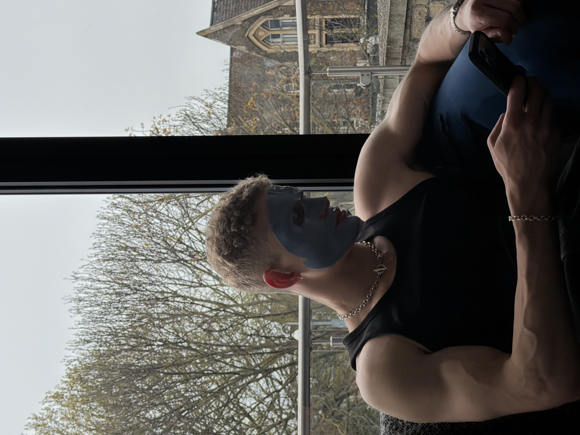 Man in blue face mask uses phone by London window