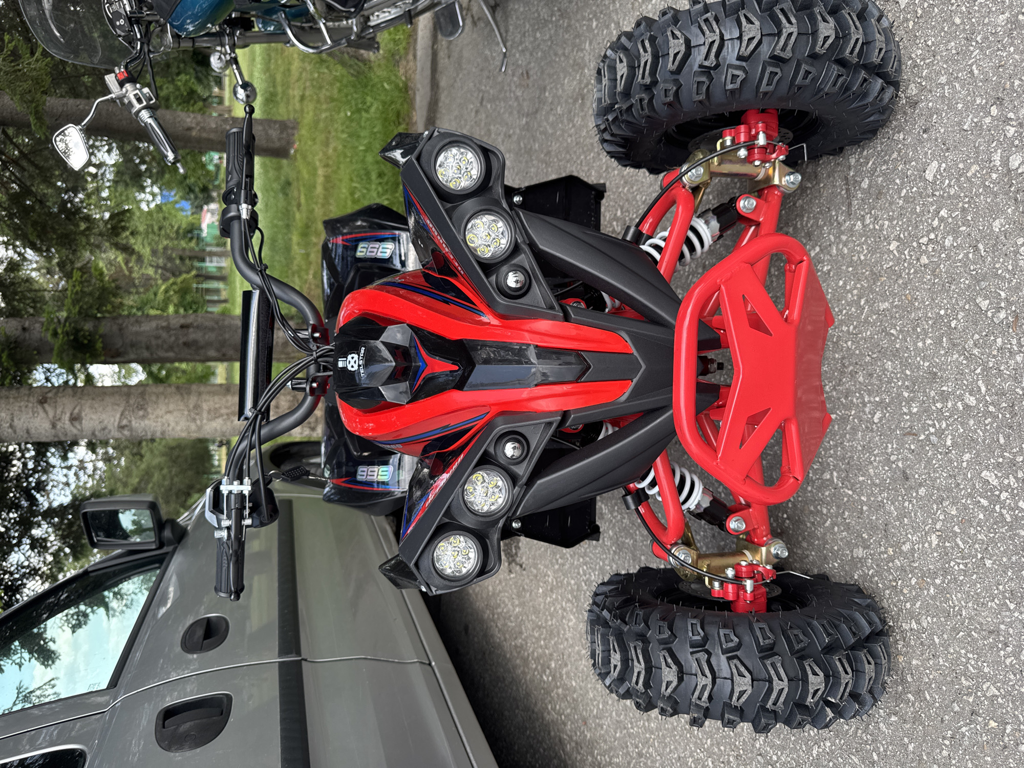 Boy rides red ATV on grass and asphalt surfaces