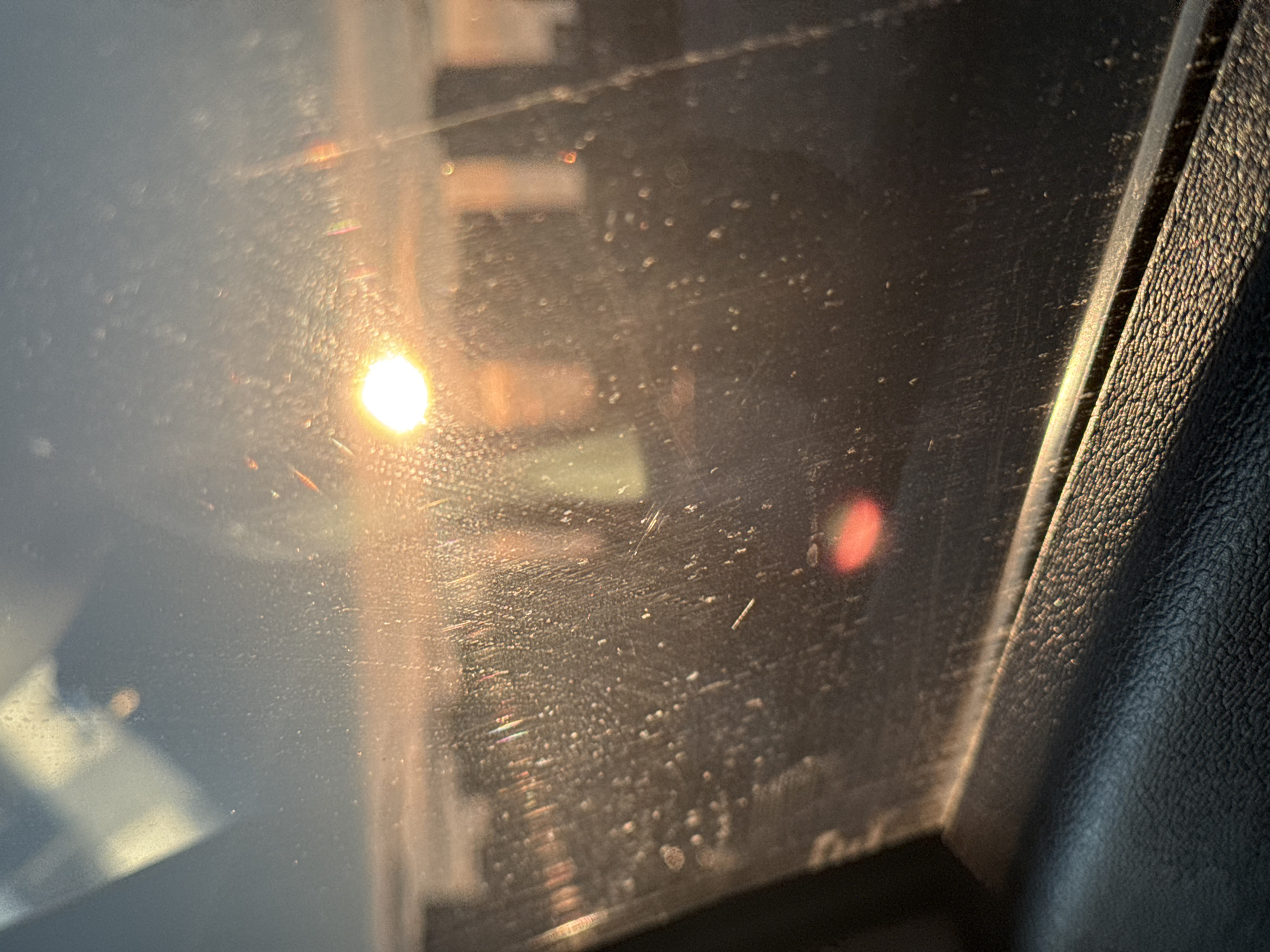Car window view captures sunlight, urban reflections