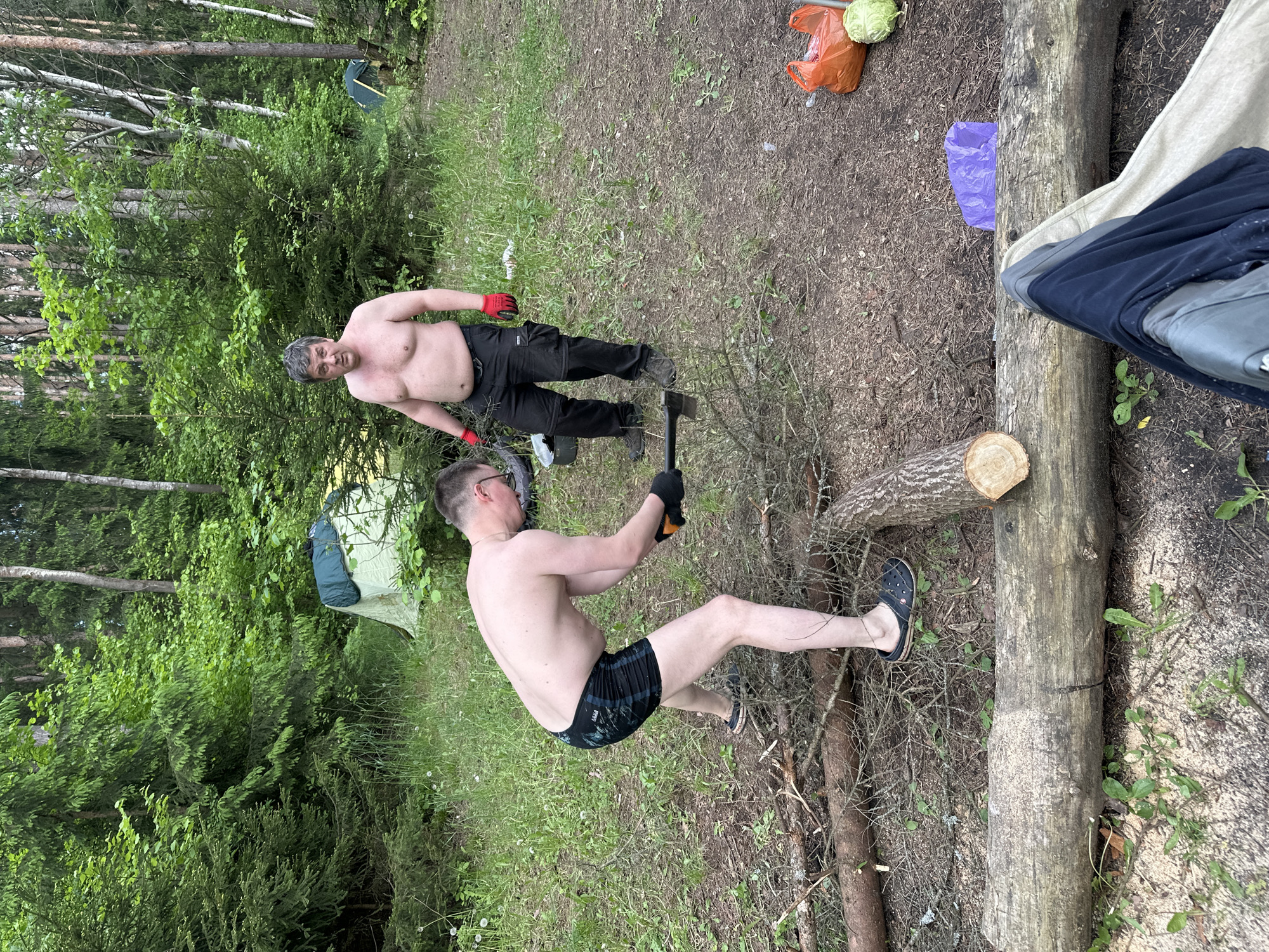 Men camping, preparing firewood at Belarus lakeside location