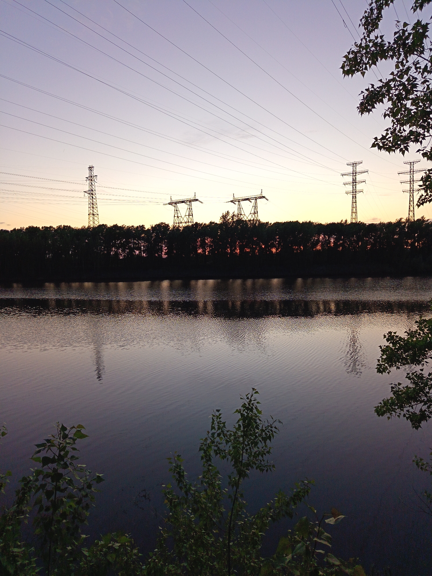 Peaceful waterside scene with power lines near Chaikovsky