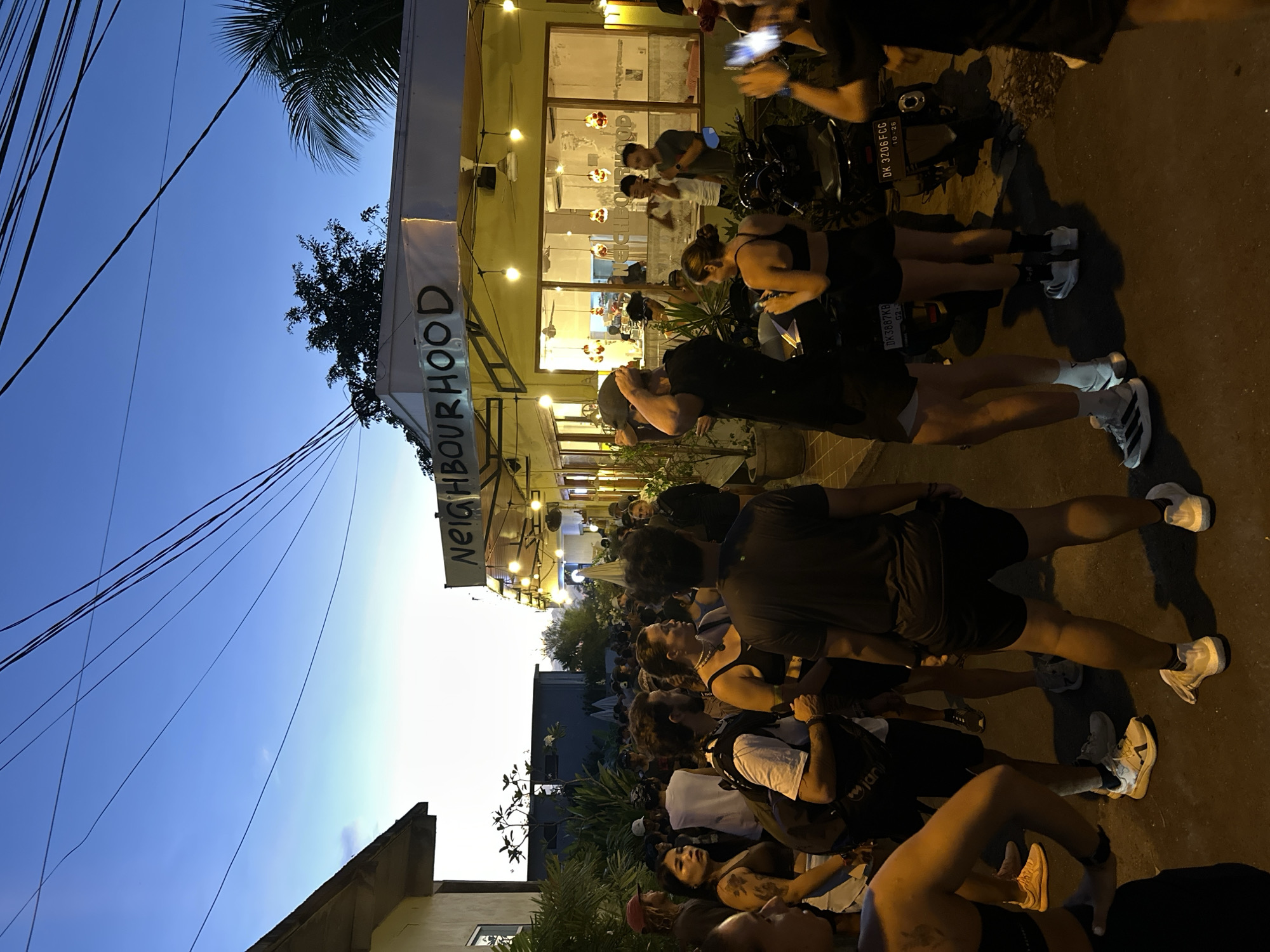 Crowd gathers at dusk outside Cemagi neighborhood building
