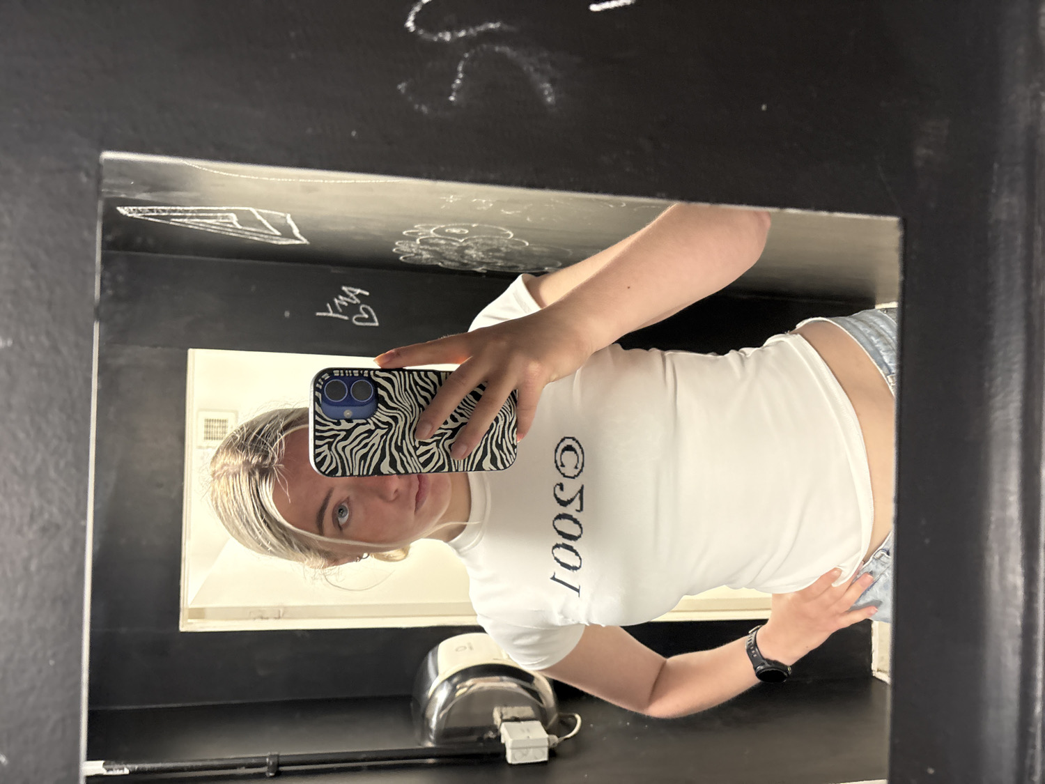 Woman takes mirror selfie in graffitied Manchester interior