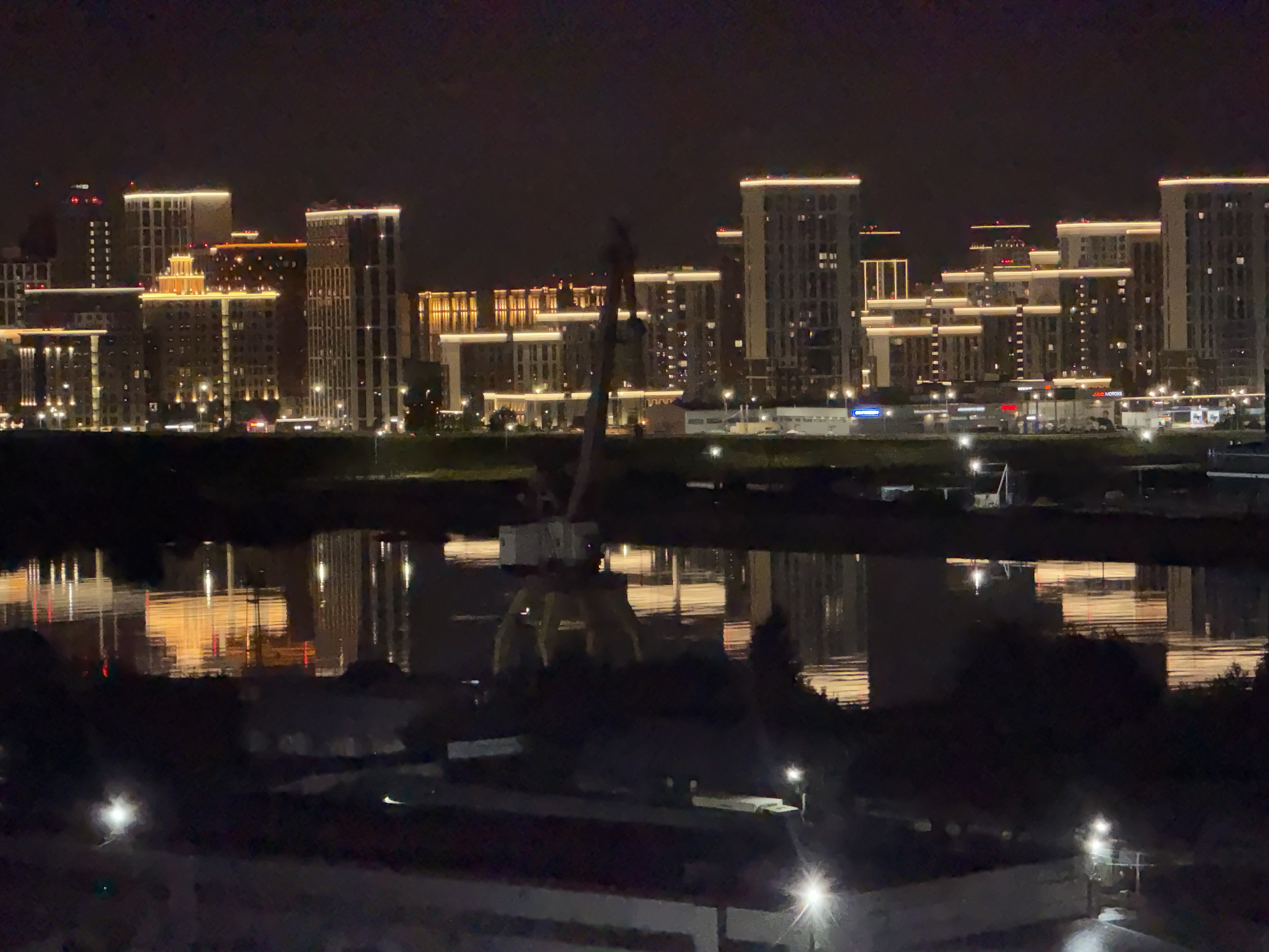 Tyumen's illuminated skyline reflects across the waterfront at night