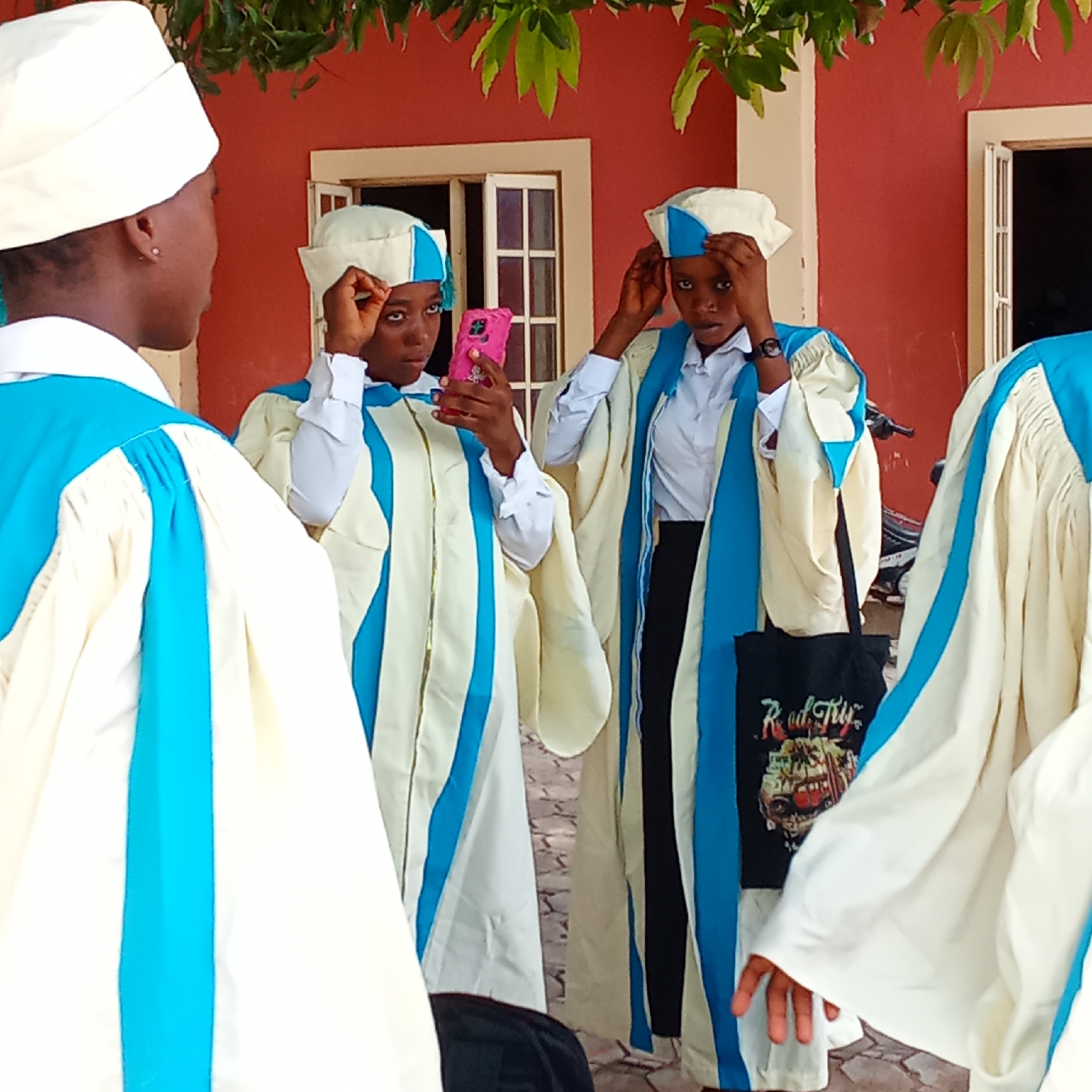 Robed group gathers outside building, member holds pink phone