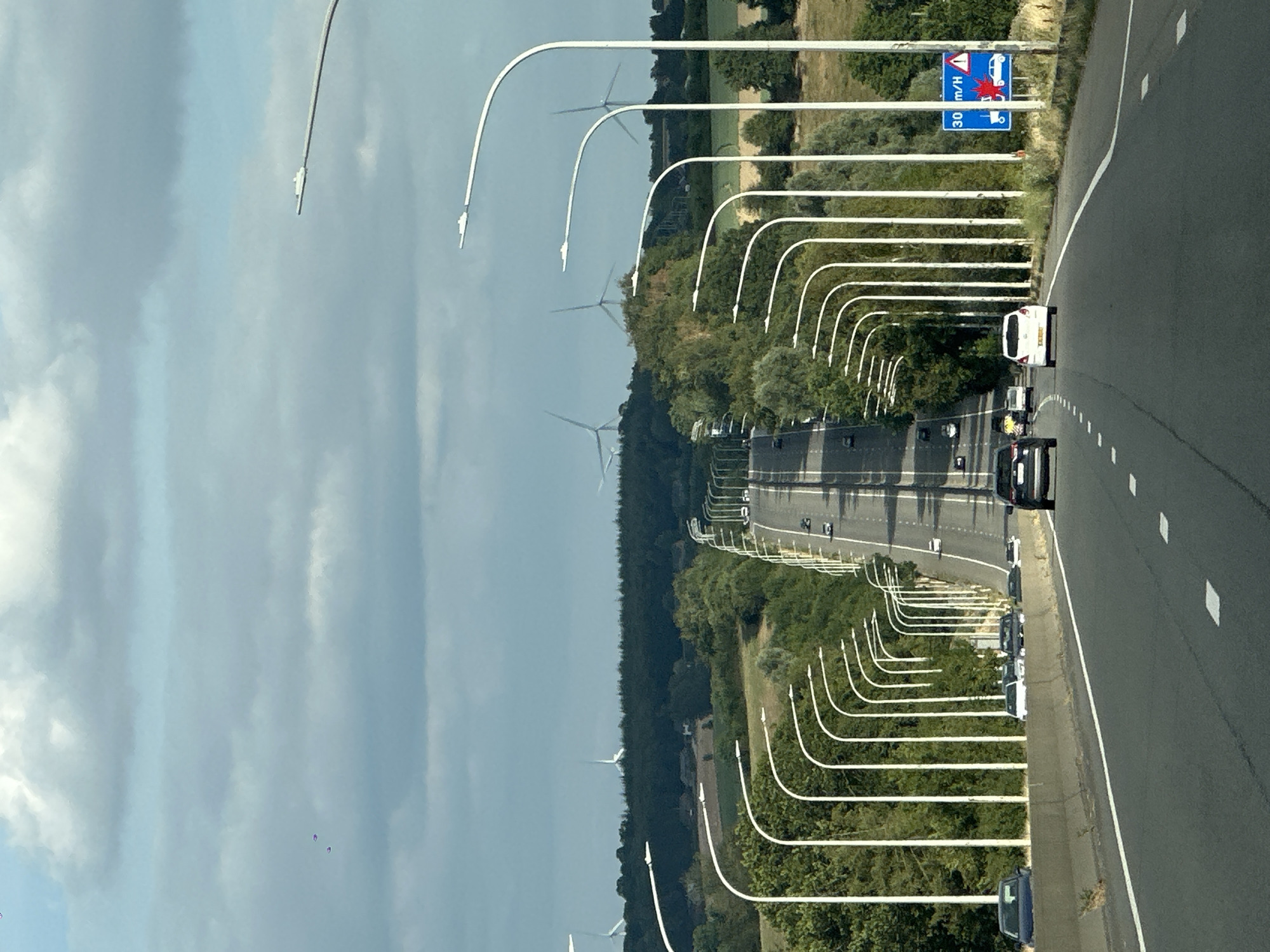 Empty Belgian highway lined with streetlights and green hills