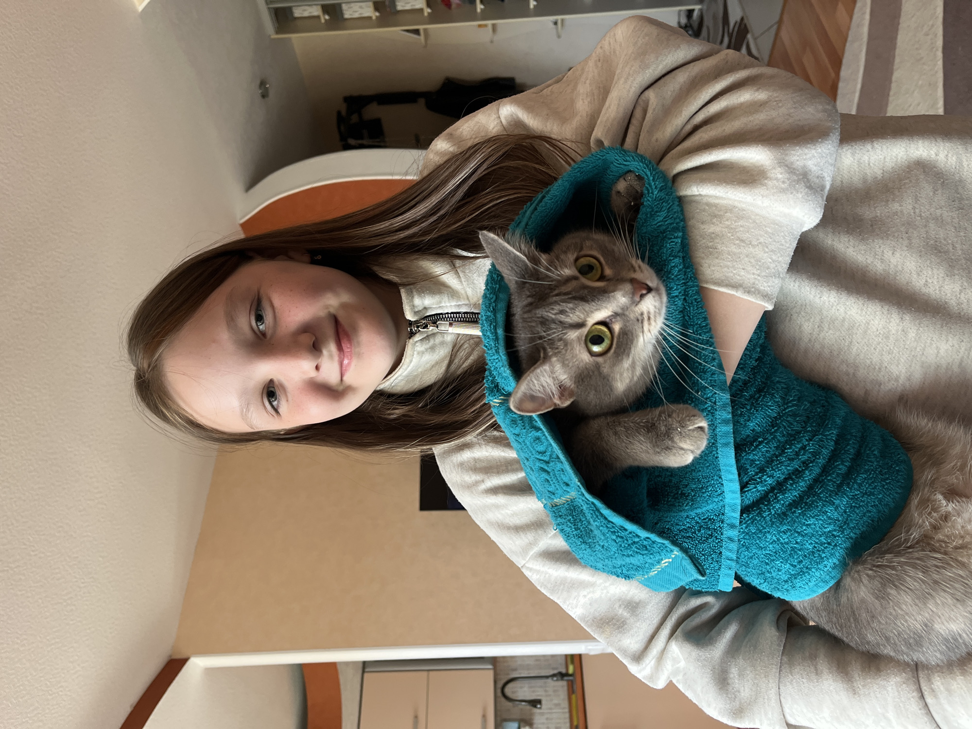Woman holds gray cat in towel, Chaikovsky Russia