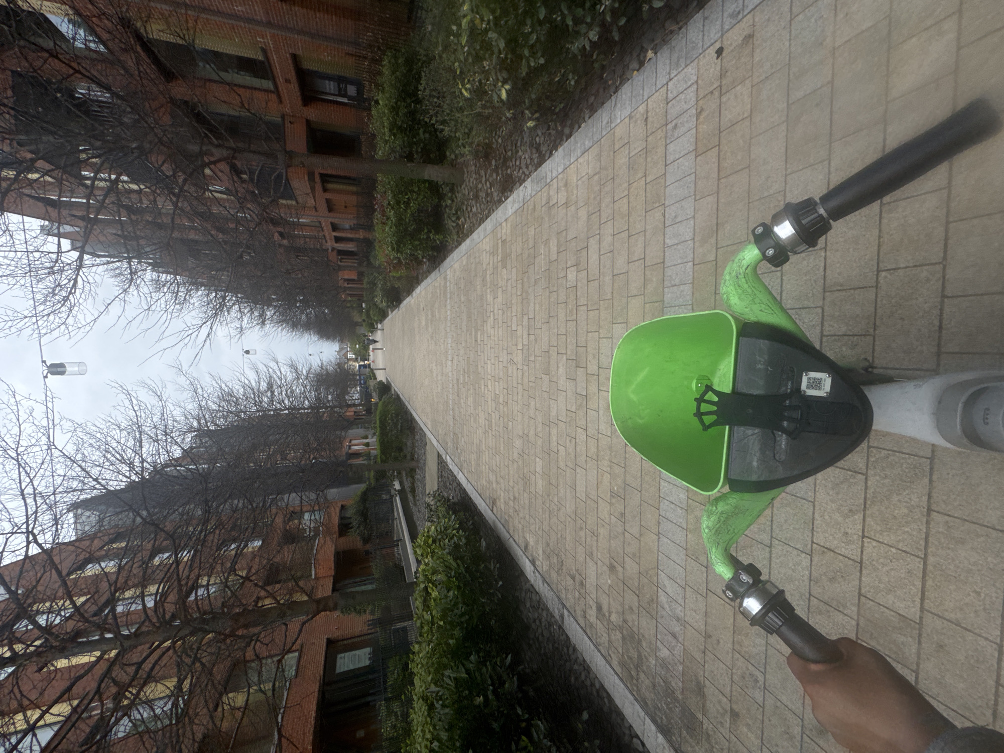 Person rides electric scooter on brick pathway in London