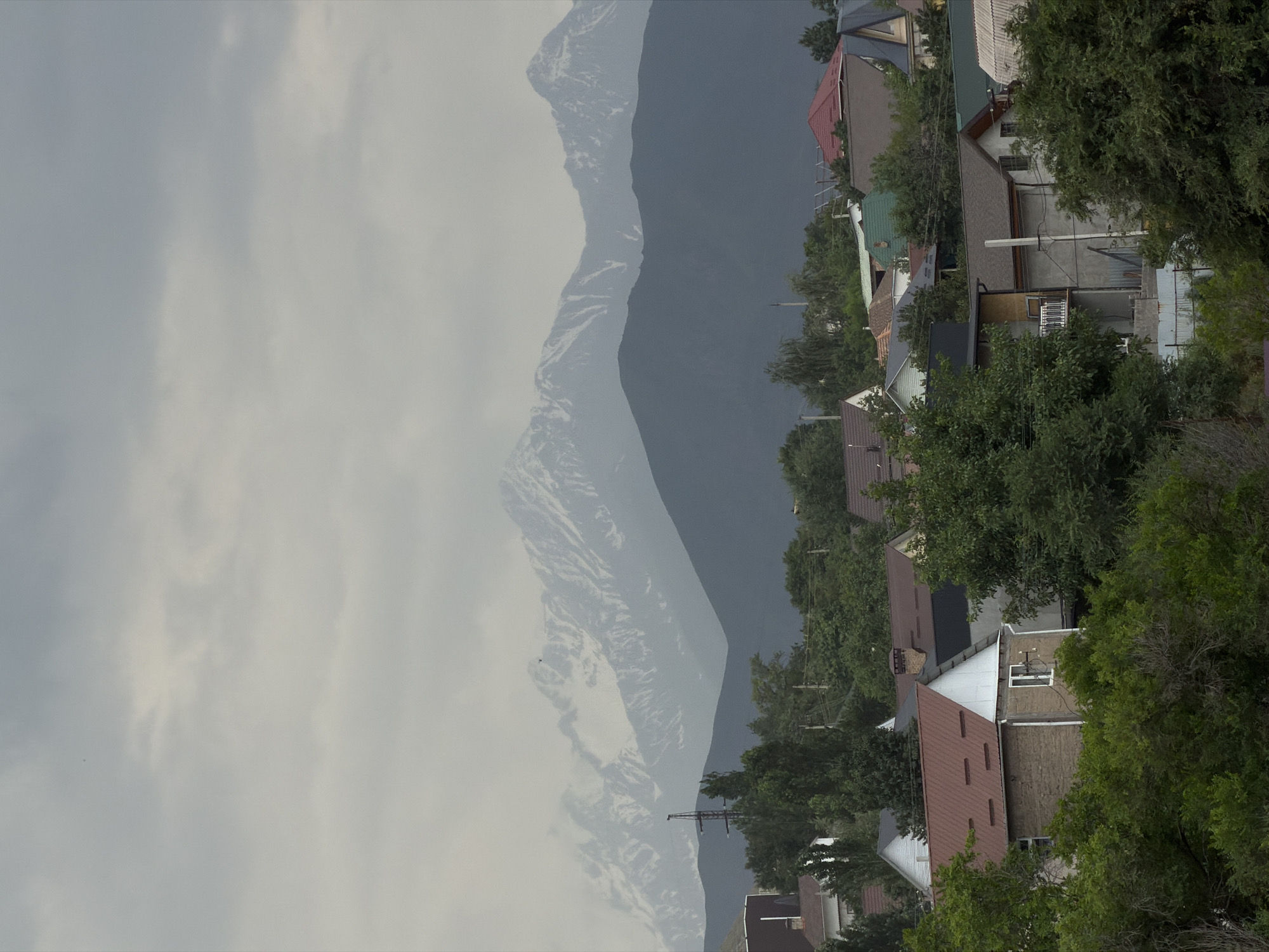 Mountain valley life: horses, livestock, a church, and cloudy peaks