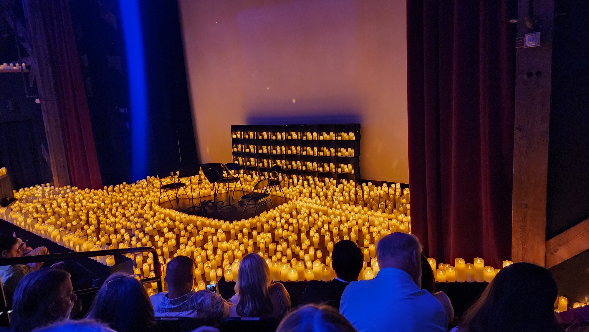 Candlelit concert stage glows with hundreds of flickering lights