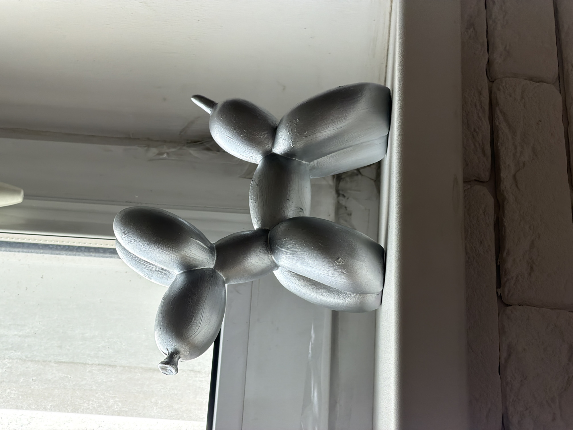 Silver balloon dog figurine spotted on window frame